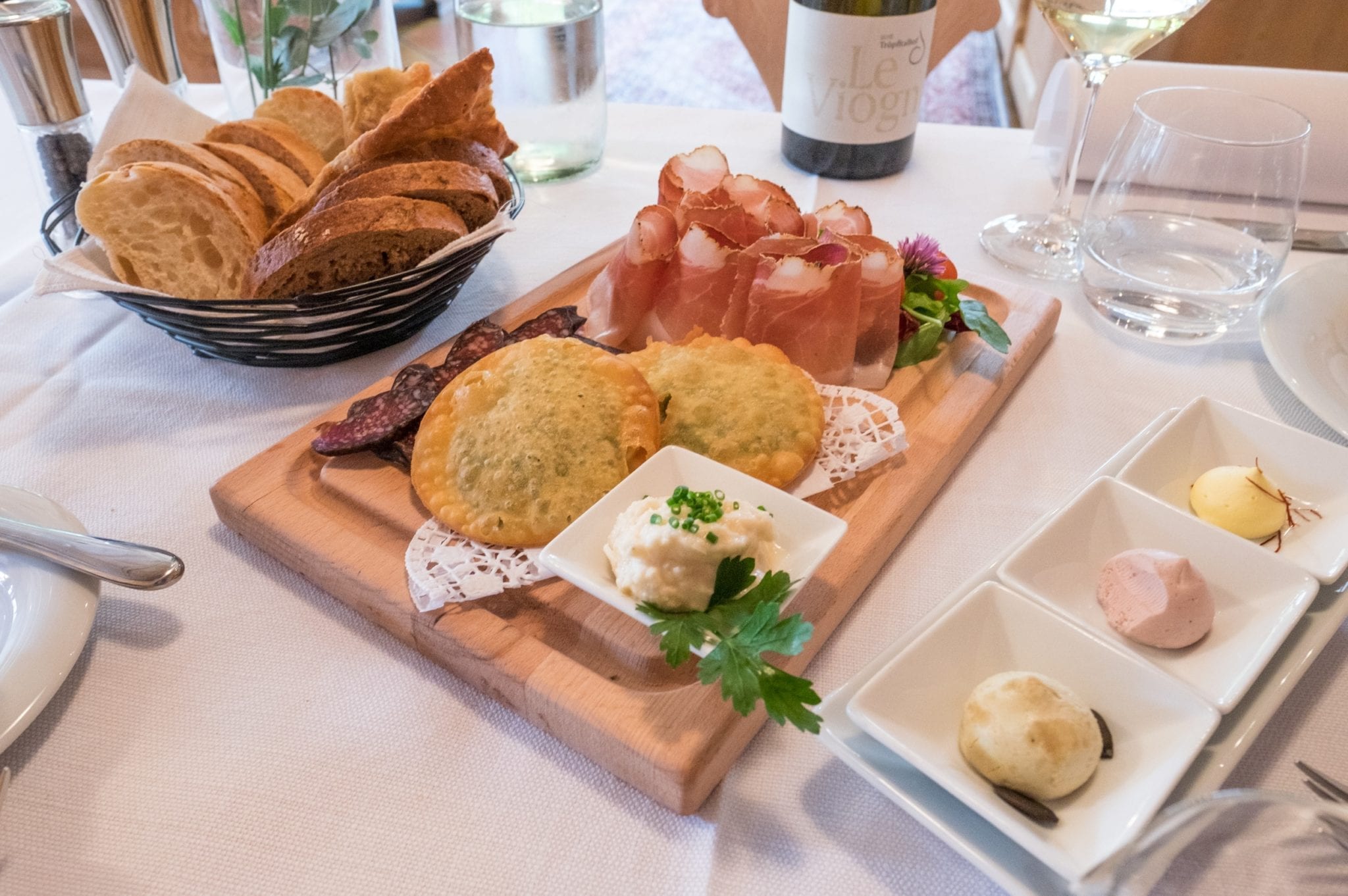 Speck with goat sausage and fried bread on a wooden platter