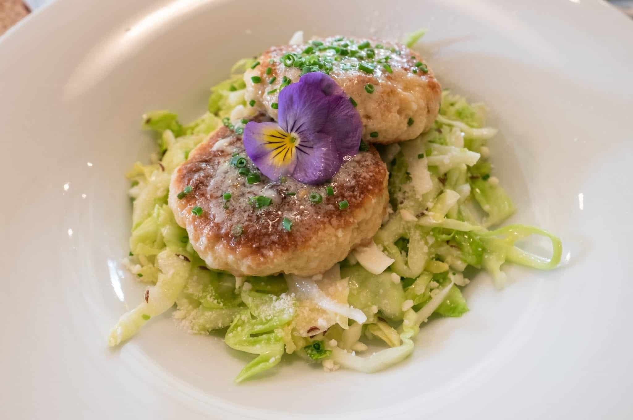 Pressknodel: bread dumplings on the top of a pile of cabbage with a decorative purple flower on top