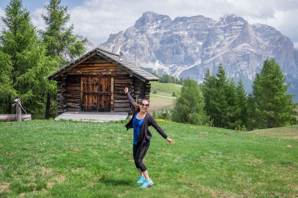 Kate twirls around with a hut and mountain behind her