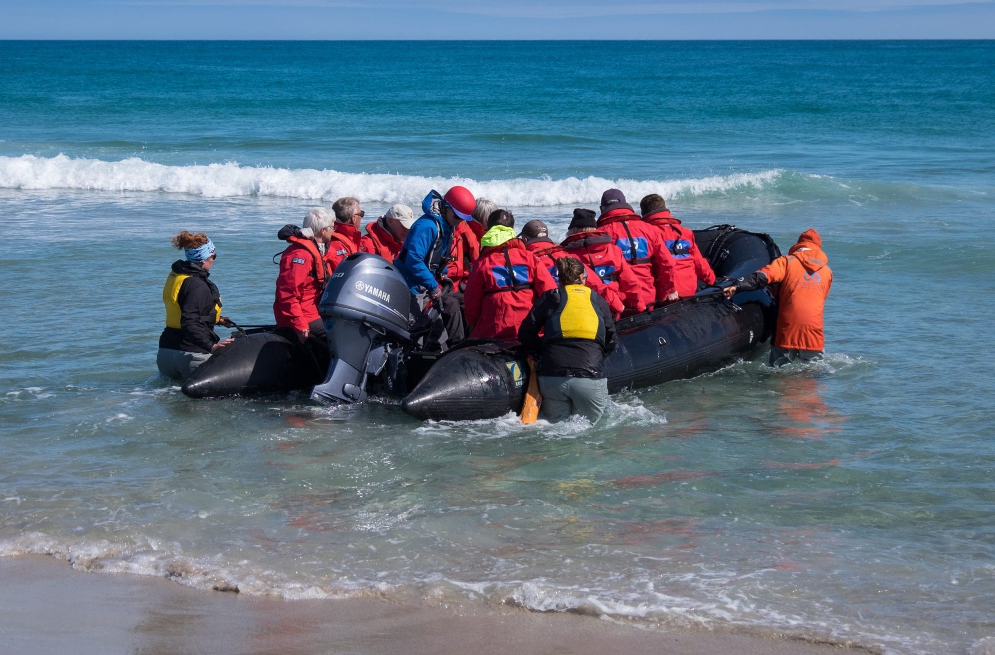 A zodiac full of people launches into the bright blue ocean off Sable Island.