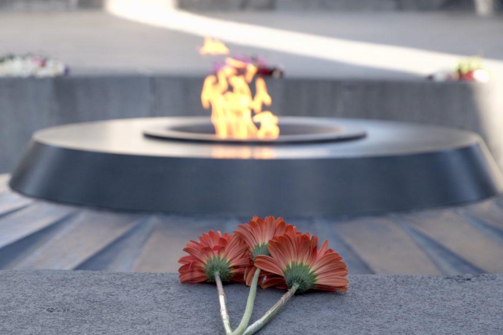 Three red flowers placed in front of there eternal flame at the Armenian Genocide Memorial.