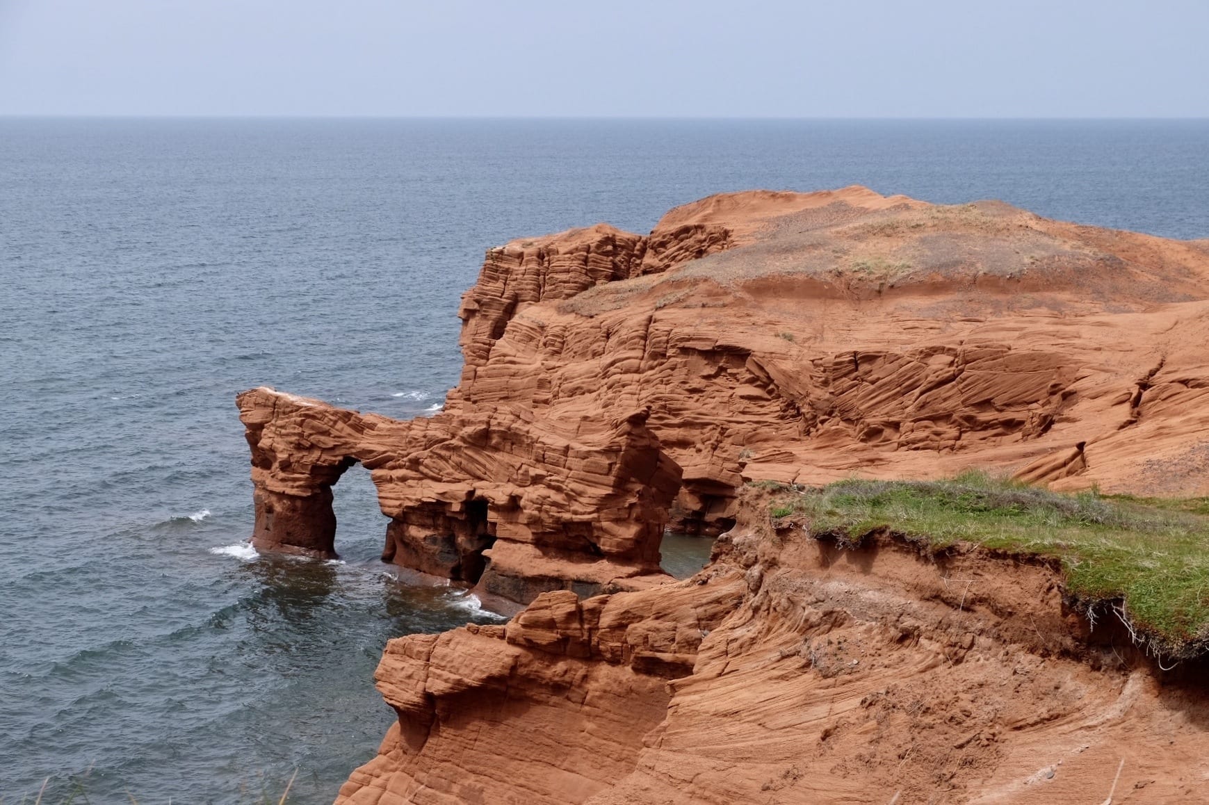 Bright red cliffs in fall into the ocean.