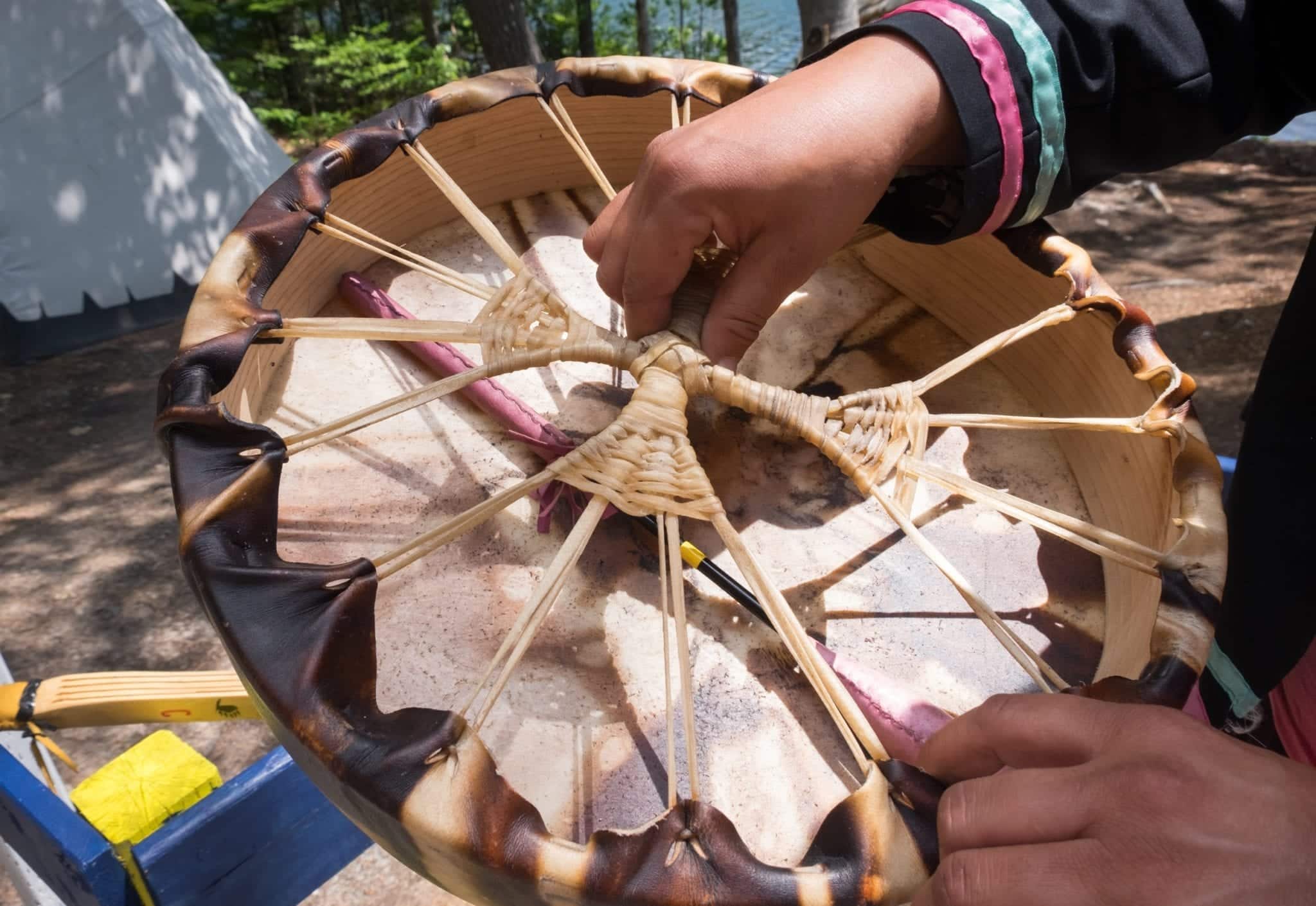 A traditional Mi'kmaq drum made from woven sinew, and a woman's hand on top.