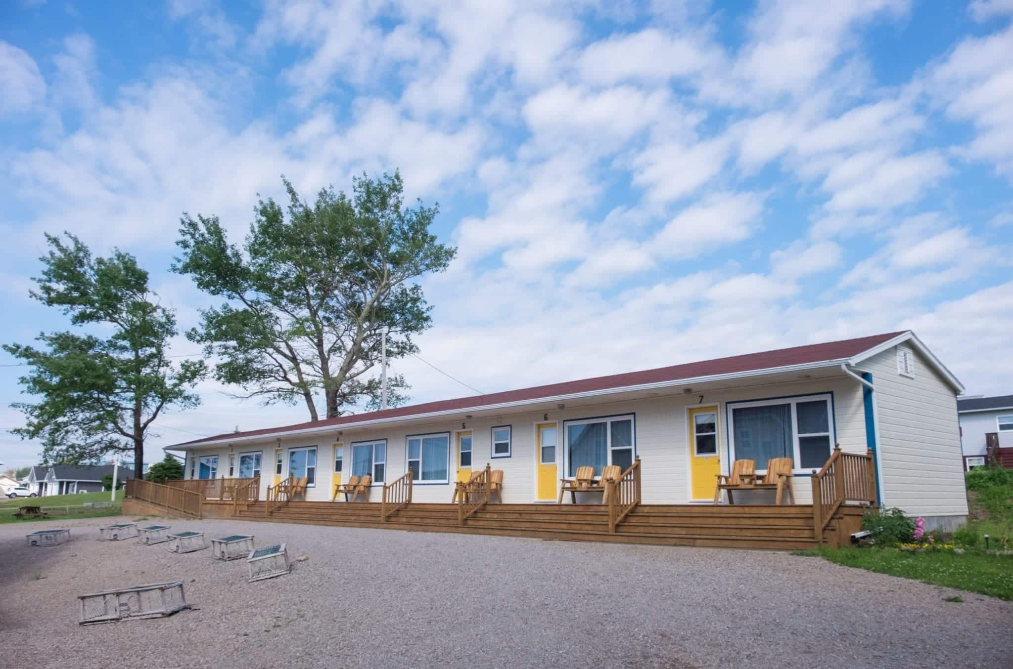 A one-story white motel underneath a blue and white spotted sky.