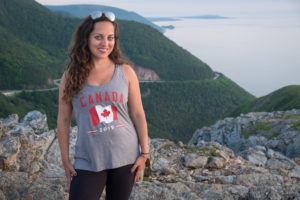 Kate standing in front of the mountains wearing a "Canada 2019" tank top in Cape Breton Highlands National Park.