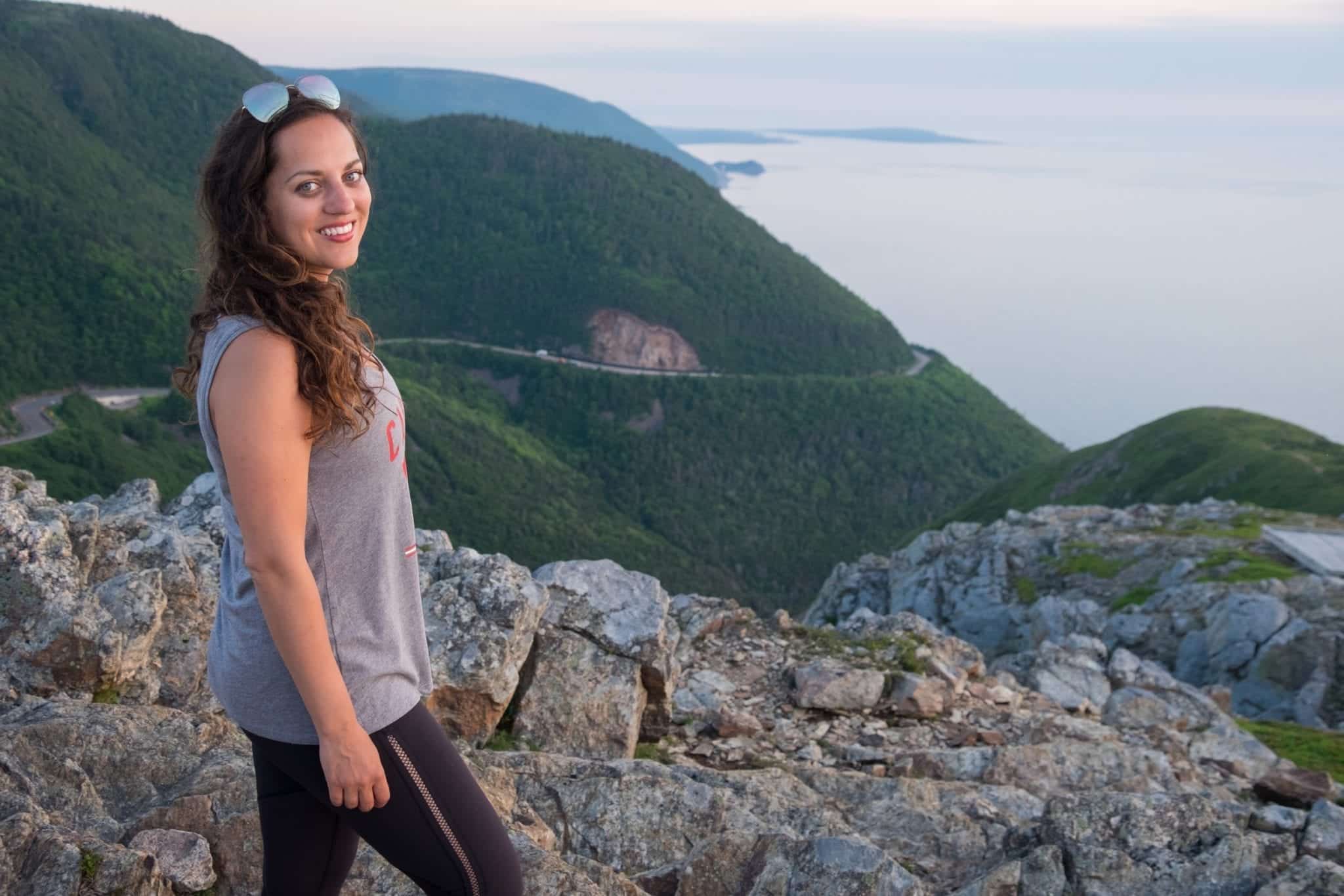 Kate standing in front of the mountains wearing a "Canada 2019" tank top in Cape Breton Highlands National Park.