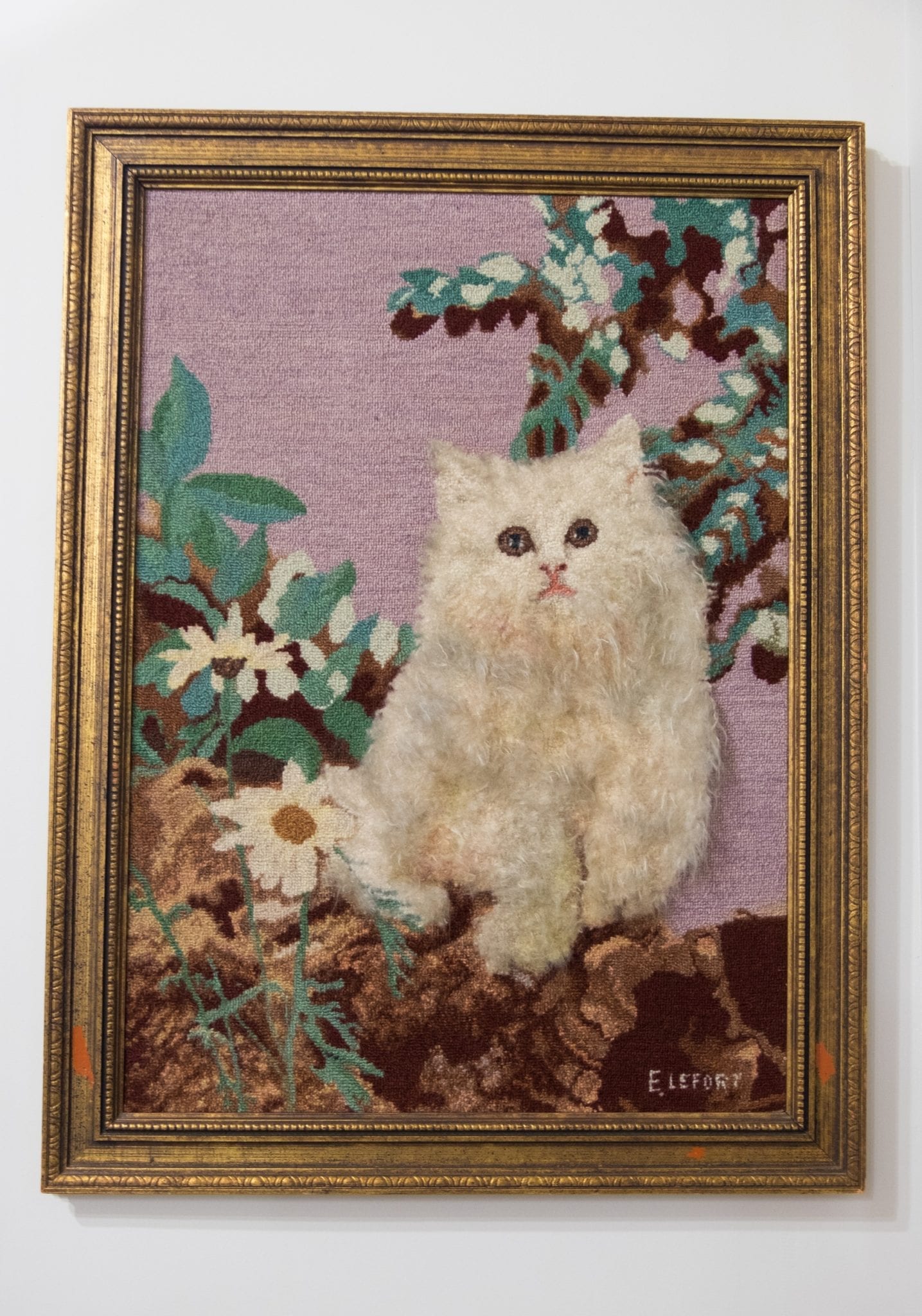 A hooked rug with a white Persian cat on it.