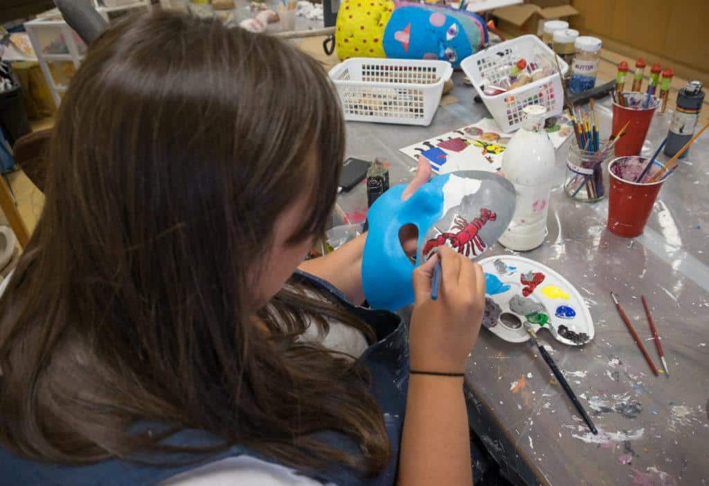 Cailin paints a lobster on her mask at the Mi-Careme Centre