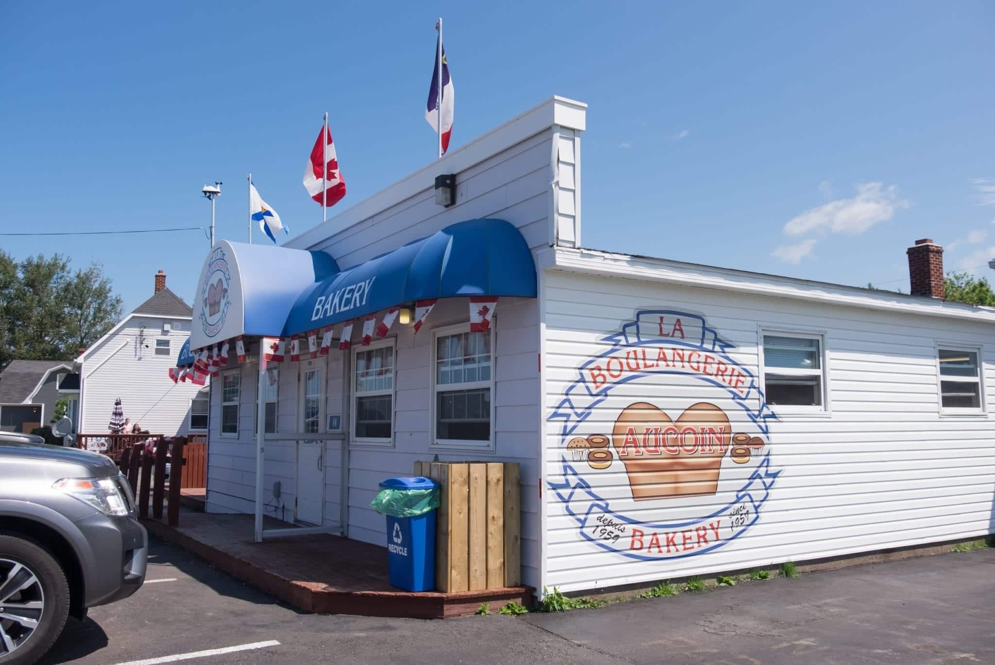 Red, white, and blue Aucoin Bakery with flags waving in the air above it.