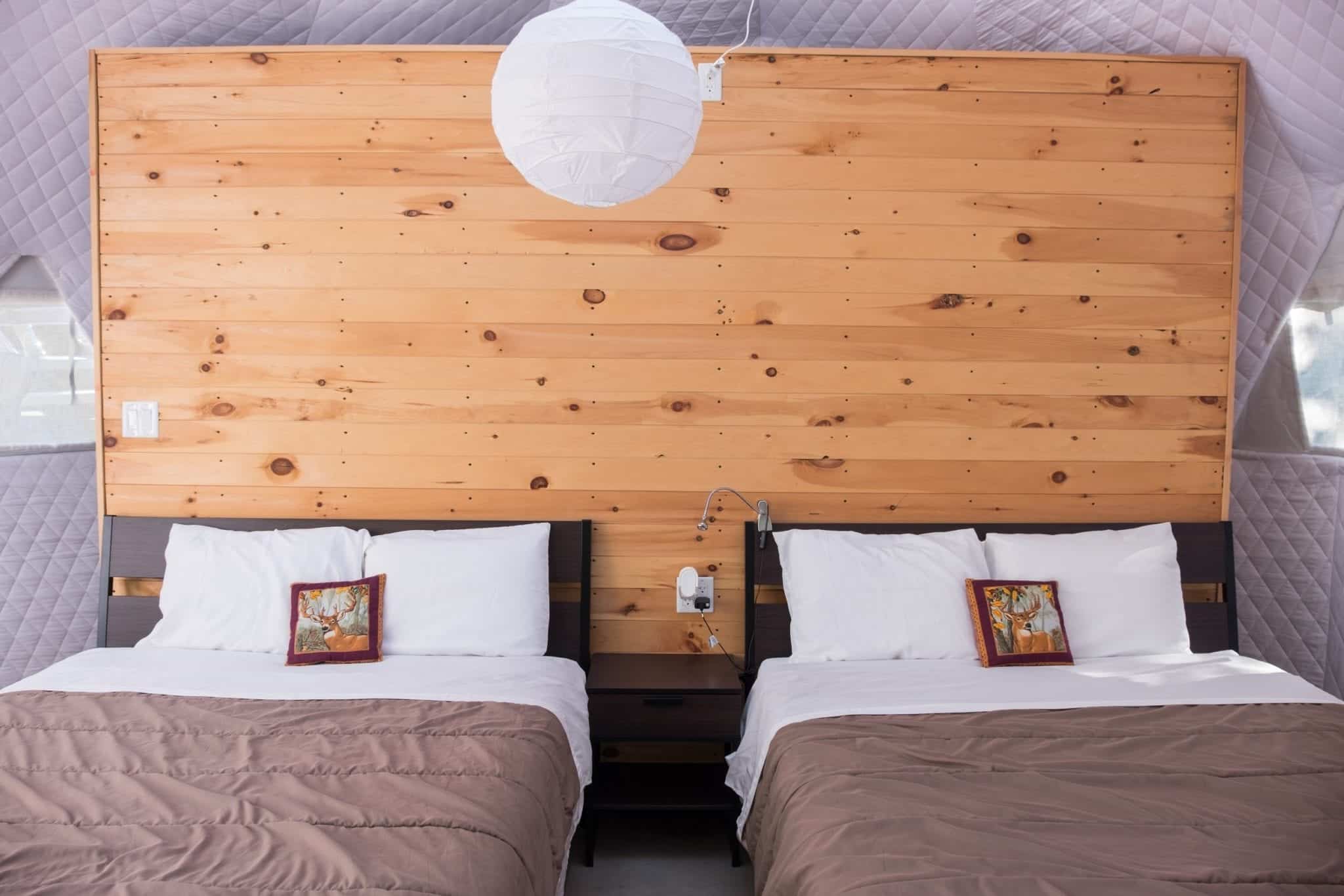 Two beds side by side with a wooden wall blinds them in the Blue Bayou Geodesic Domes