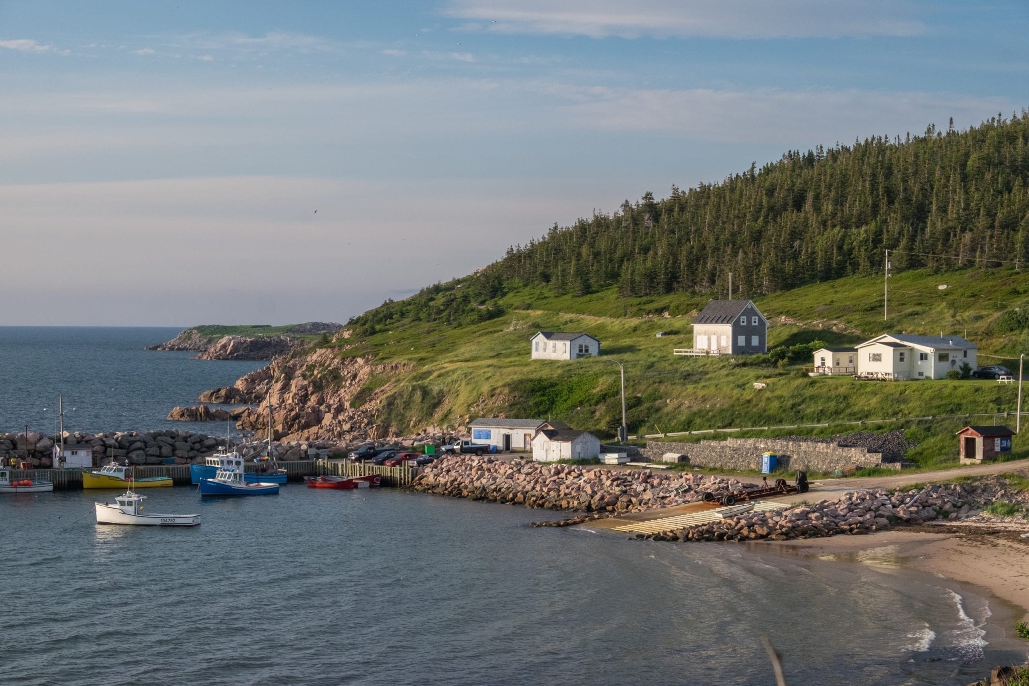 A small village next to the sea with several houses illuminated by the setting sun.