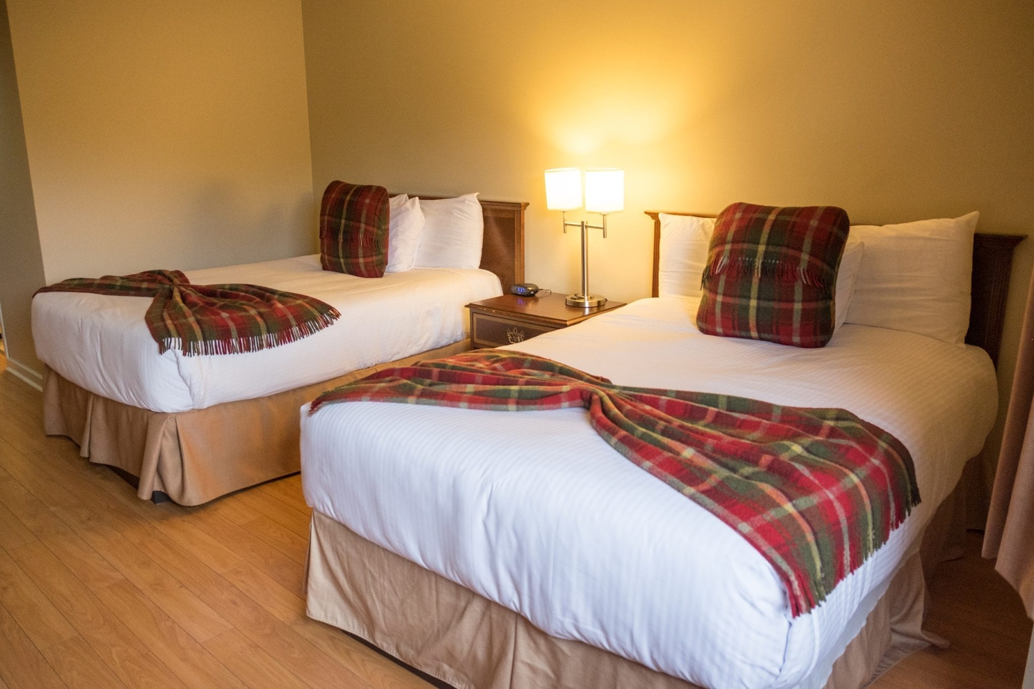 Two queen beds with plain blankets at the foot.