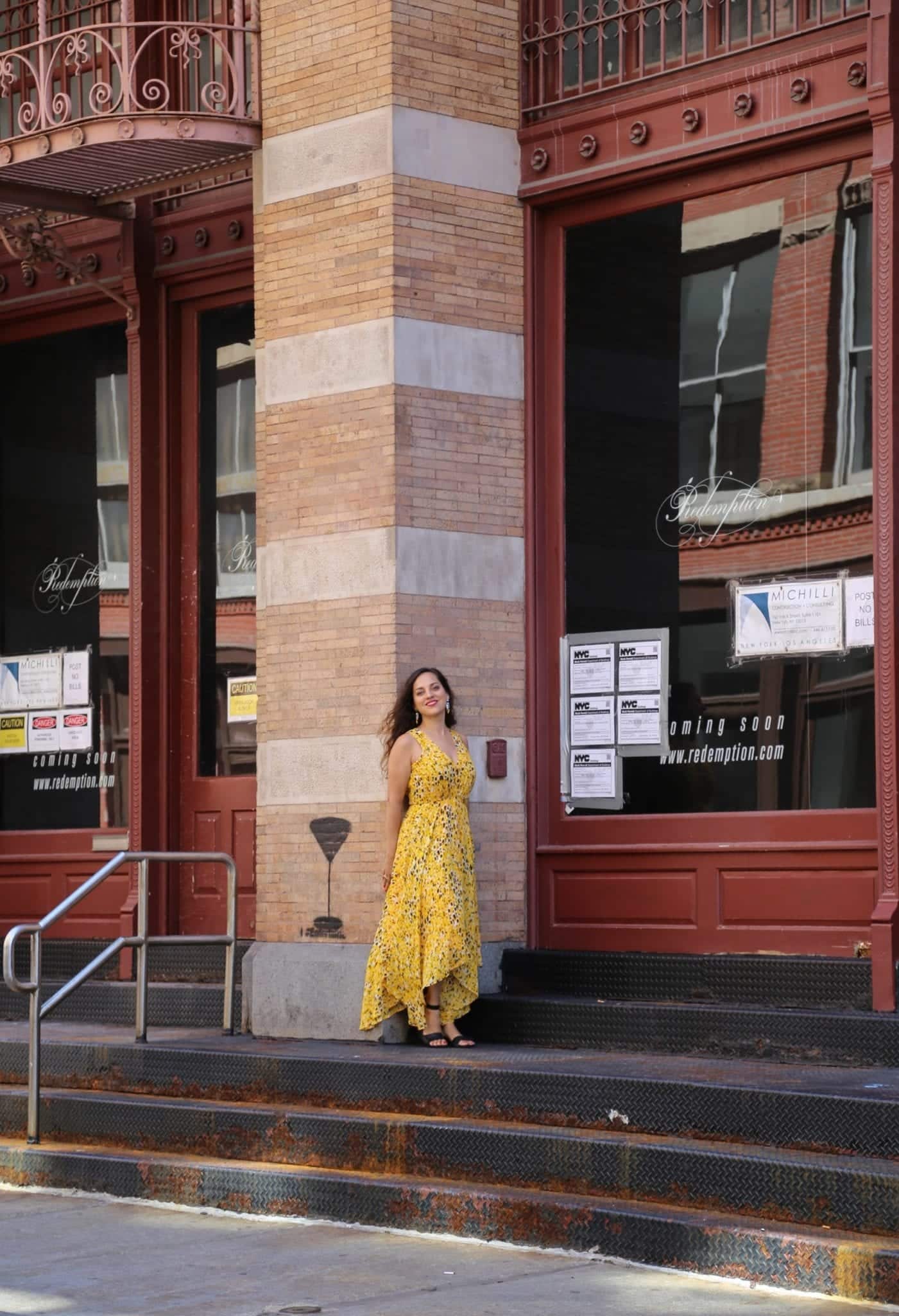 Kate standing in front of a column in a yellow dress in SoHo, NYC.