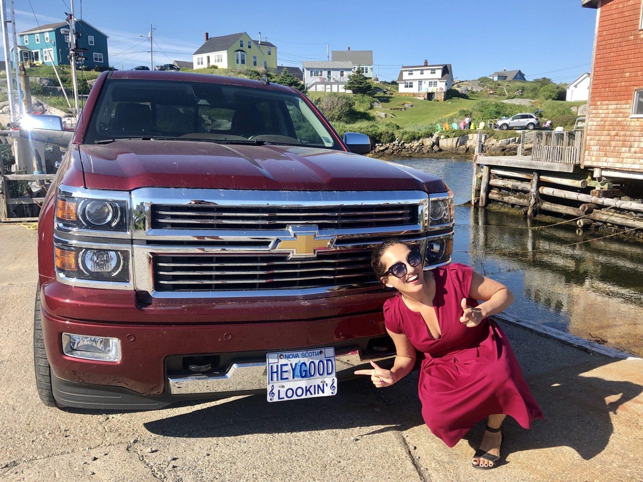 Kate gives two thumbs up in front of a pickup truck with a license plate that reads "HEY GOOD" and a sign beneath that says "LOOKIN."