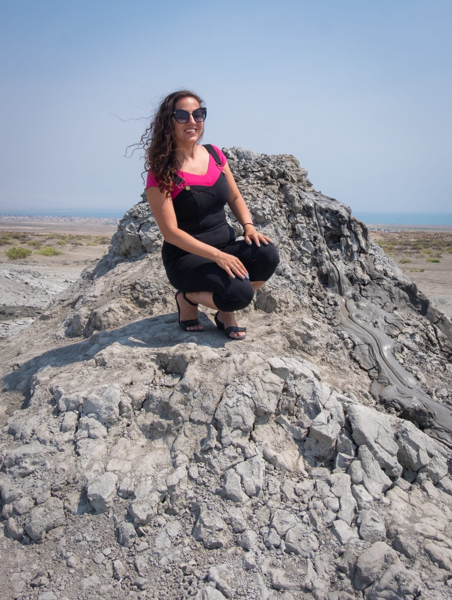 Kate crouches near the edge of a gray bubbling mud volcano.