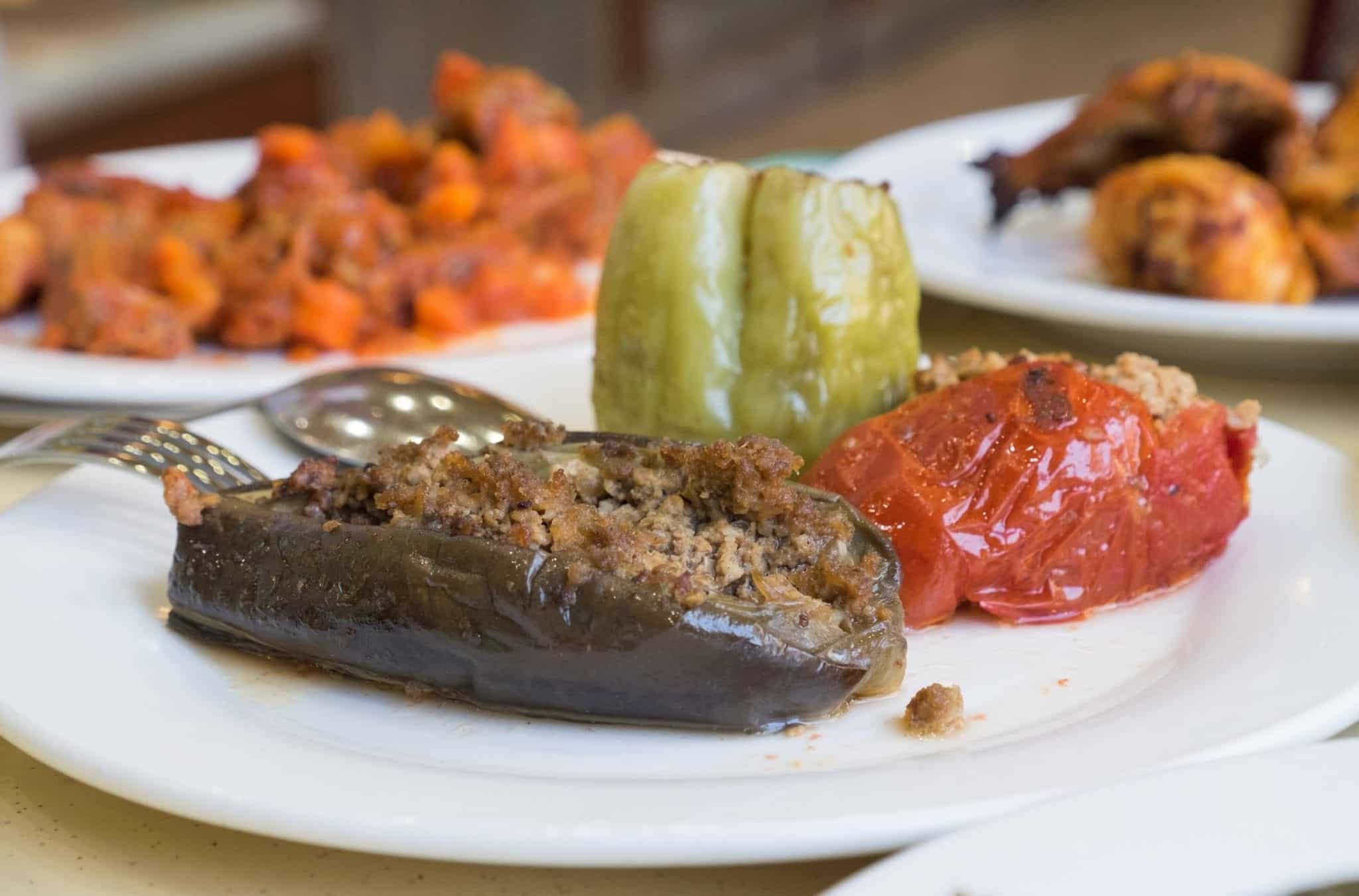  Sur une assiette, une aubergine et deux sortes de poivrons farcis au bœuf haché.