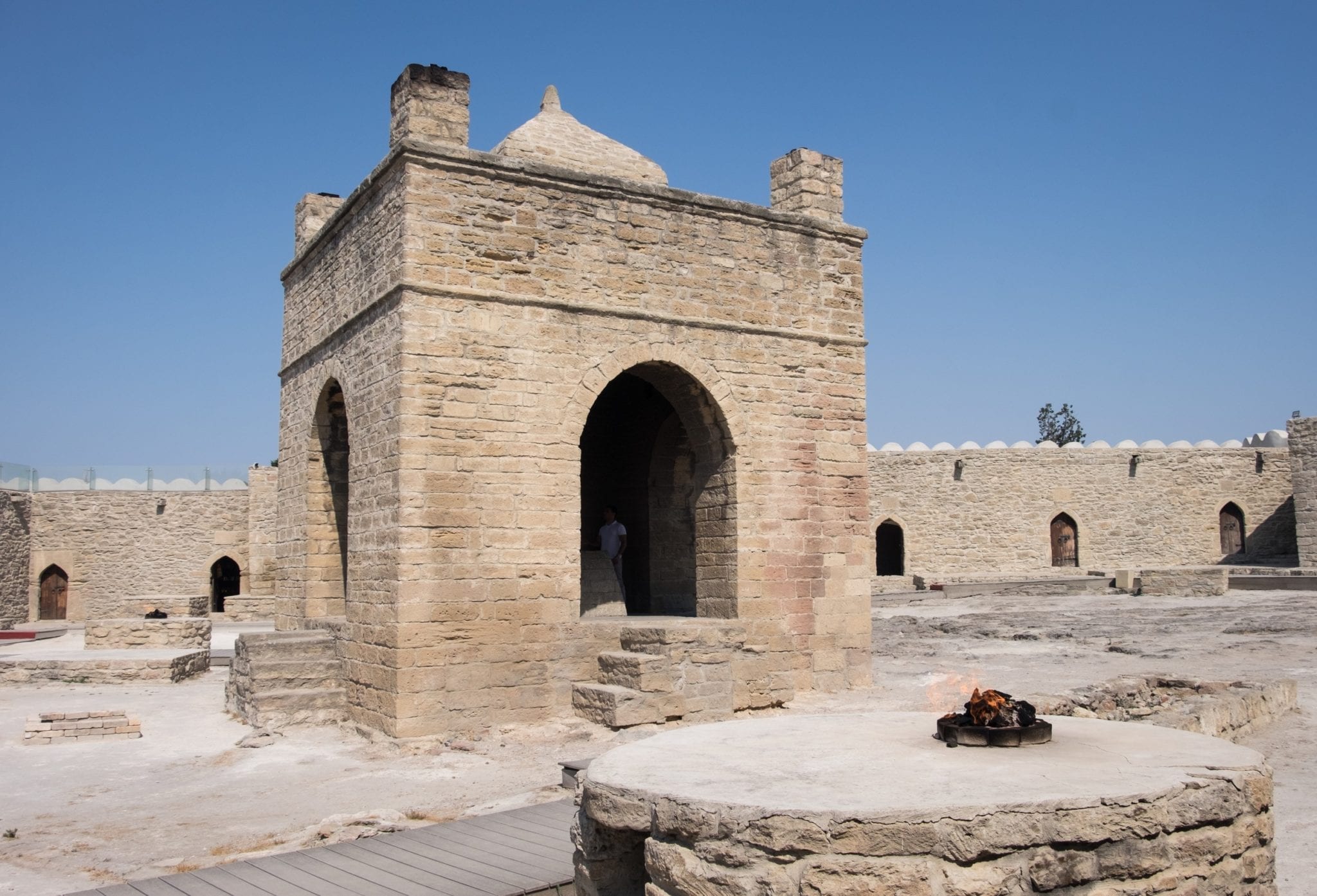 Der Tempel von Ateshgah: Ein sandfarbener Tempel vor blauem Himmel mit einer brennenden Flamme im Inneren.