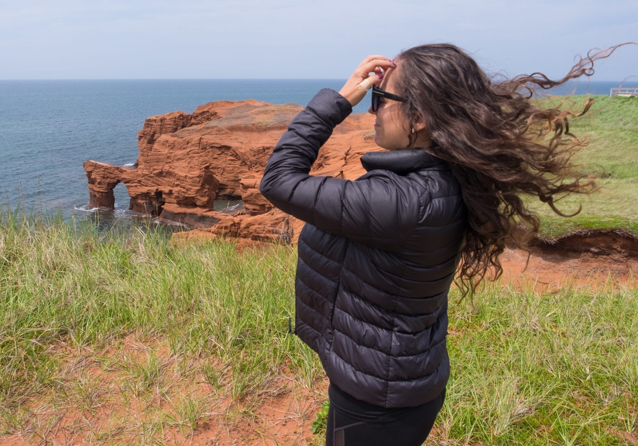 Kate stands in front of red cliffs and stands sideways to the camera, and you can see the wind is blowing her long curly hair straight upwards!