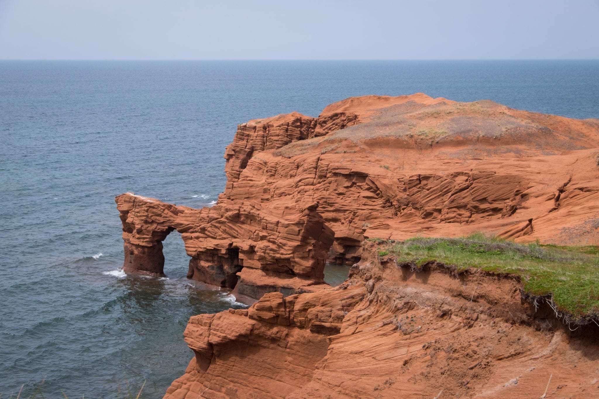 Bright red cliffs plunge into the sea on the Îles-de-la-Madeleine, Quebec.