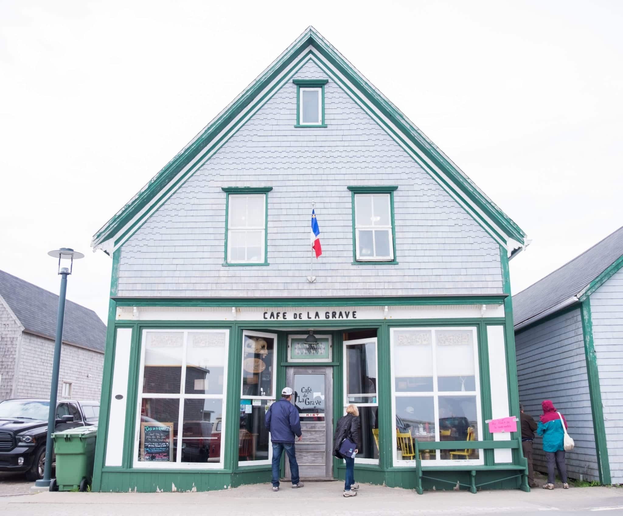 A gray house with green trim reading "Cafe de La Grave."