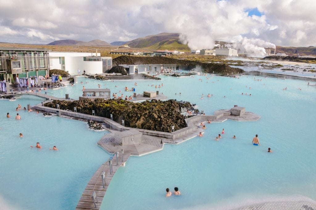 An aerial view of the Blue Lagoon, dozens of people luxuriating in milky blue water.