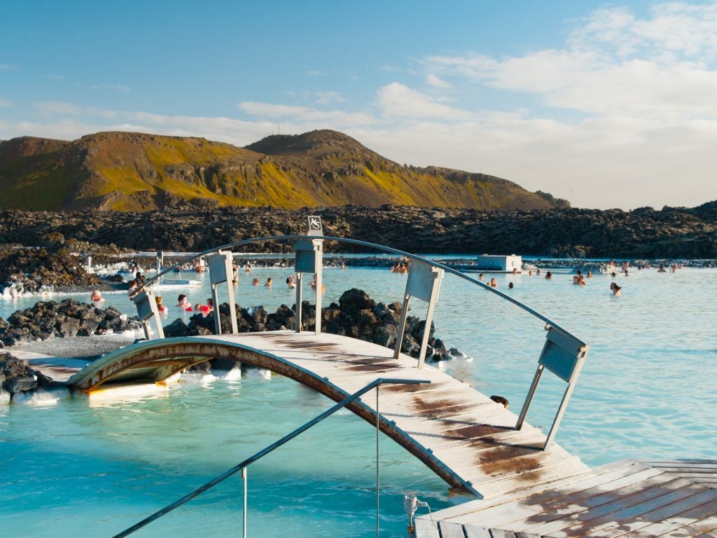 A curved bridge over the bright blue waters of the Blue Lagoon, Iceland.