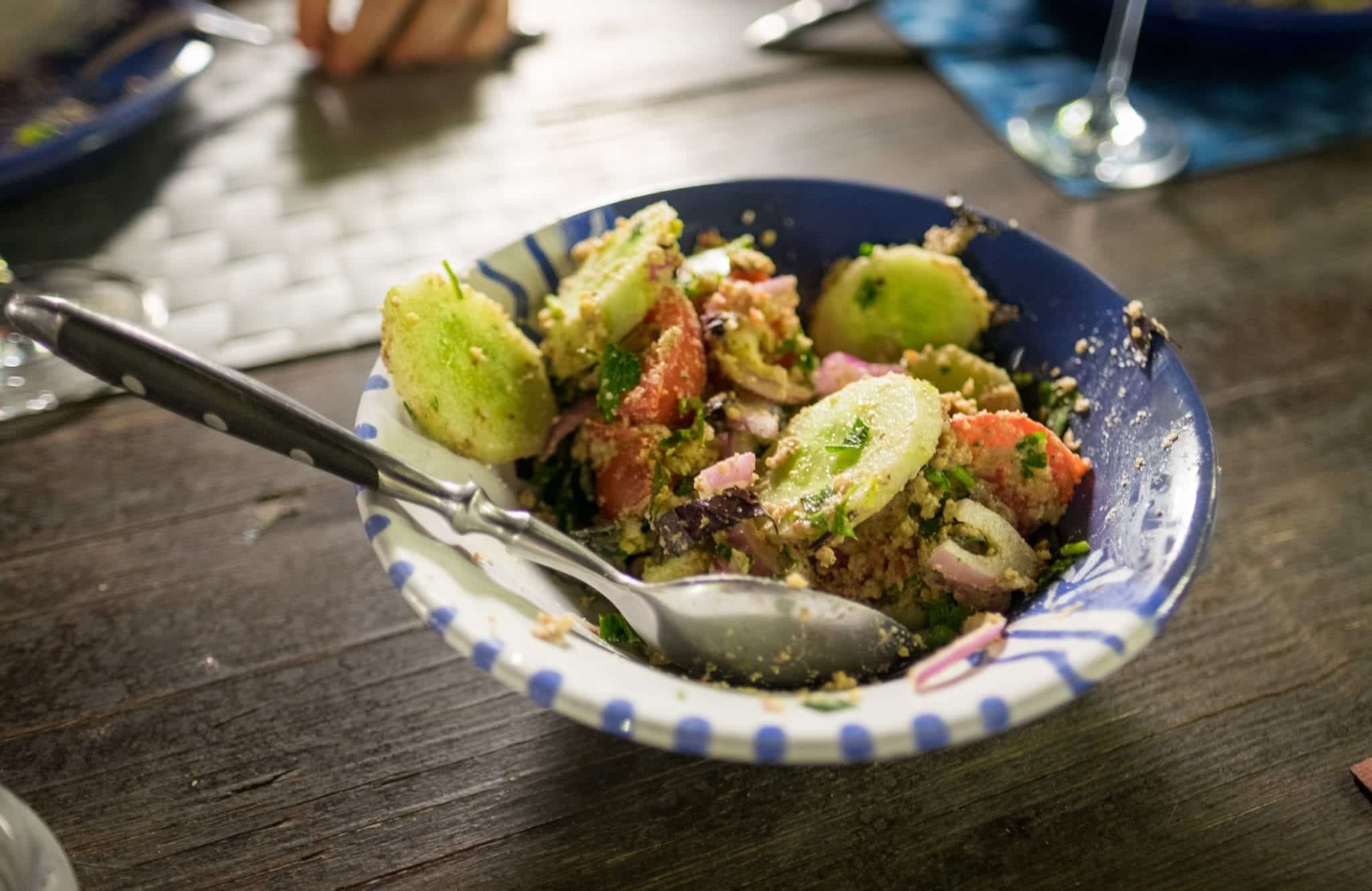 A bowl filled with cucumbers, tomatoes and red onions with walnut and herb paste.