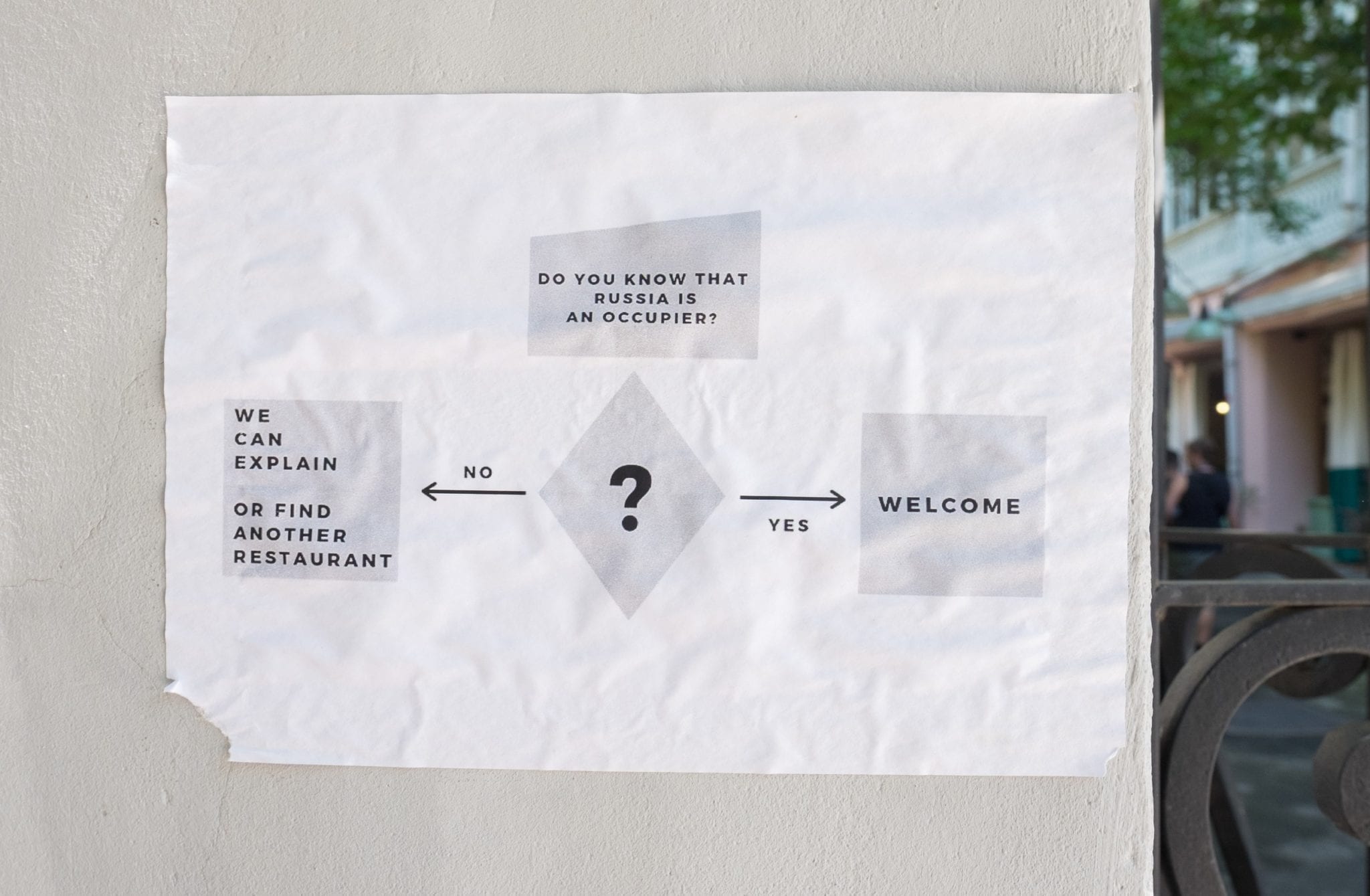 A sign with a flow chart reading, "Do you know that Russia is an Occupier?" If yes, "Welcome." If no, "We can explain or find another restaurant."