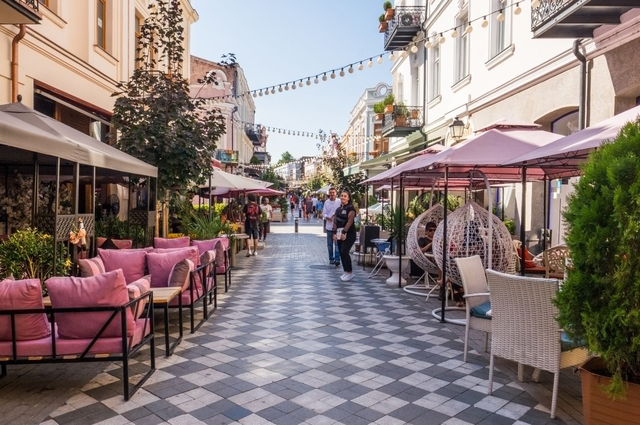 A street with restaurants on either side, waiters trying to bring customers in.