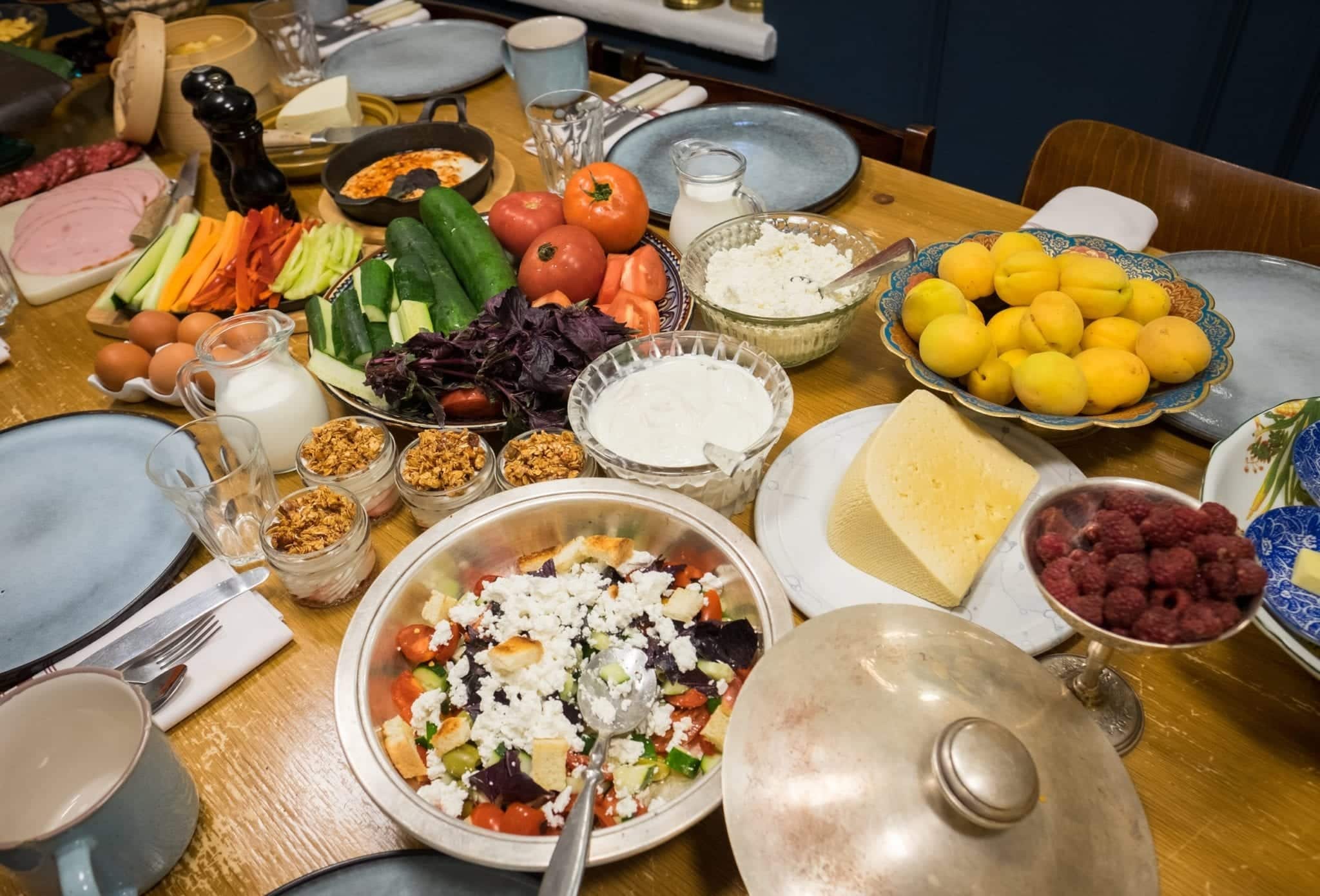 Plates of Georgian food -- salads topped with cheese, fresh vegetables, apricots, raspberries, yogurt.