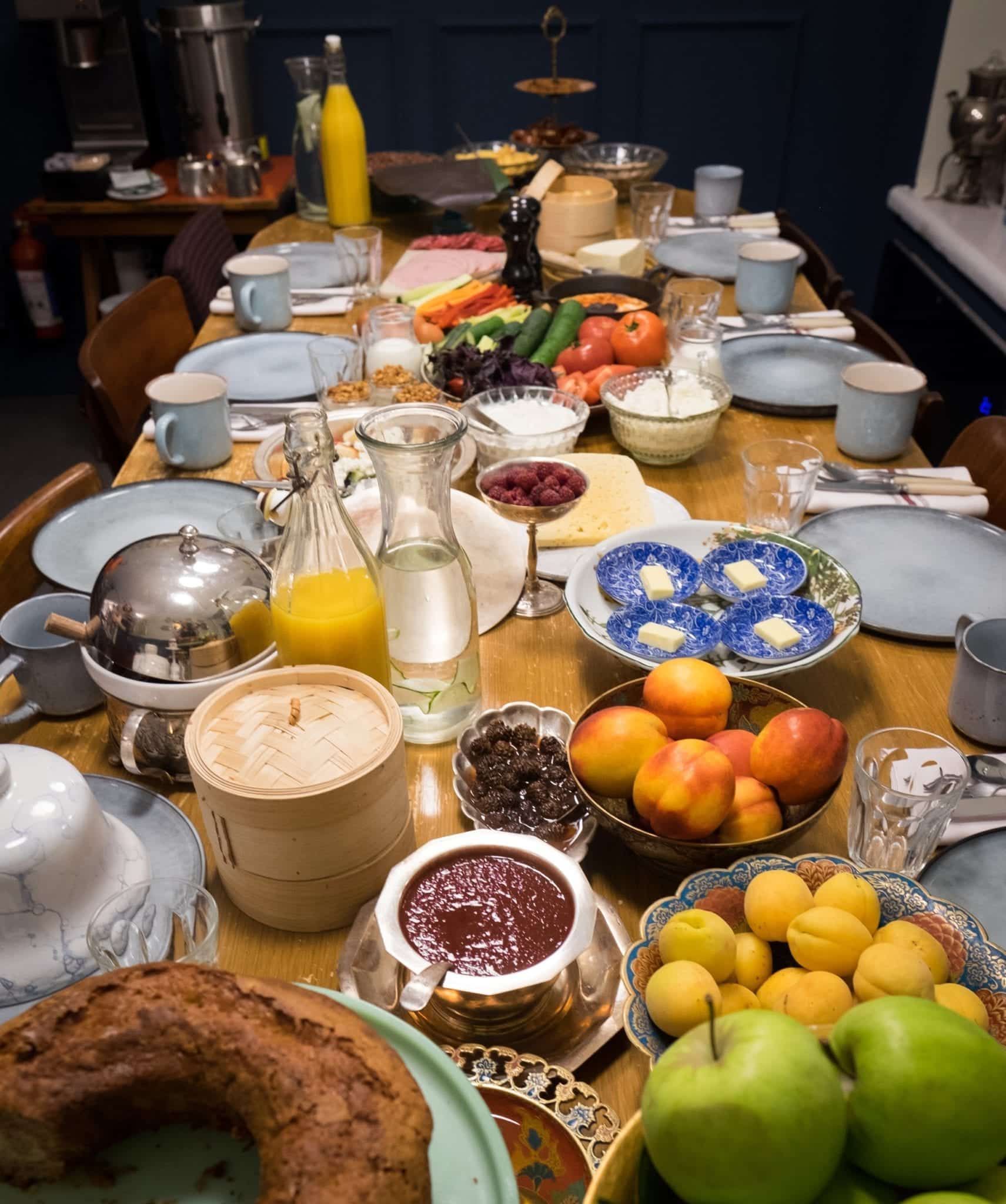 A long table brimming with breakfast: breads, fruits, pastries, cheeses, jams, all served in gorgeous blue and white dishes.