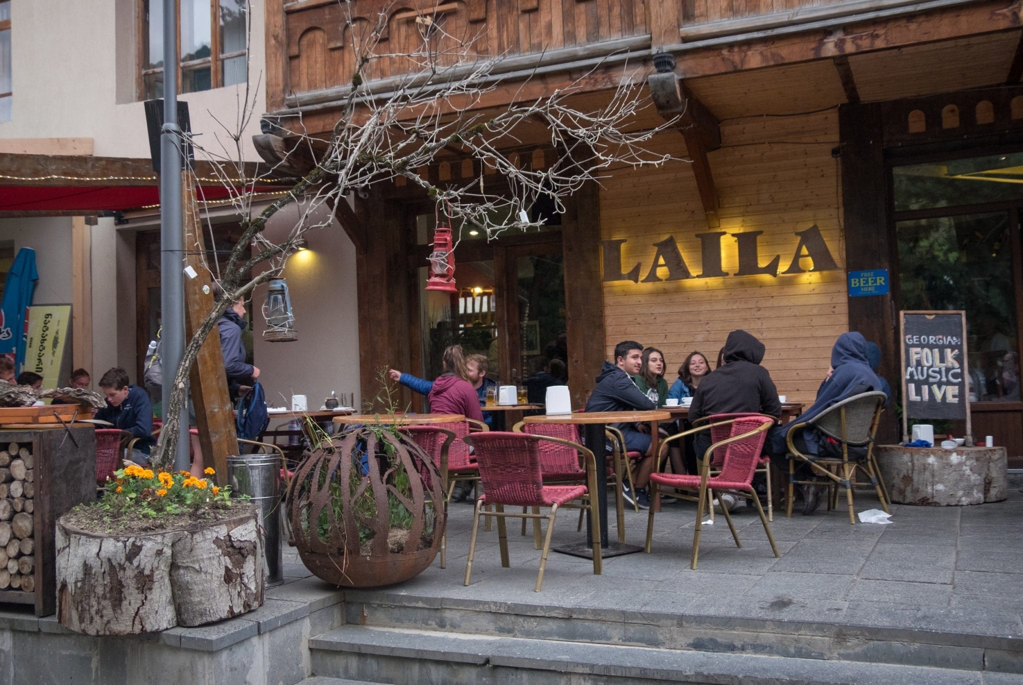 Travelers sitting outside the Laila Cad and restaurant, bundled up in the chill, in Mestia, Svaneti.