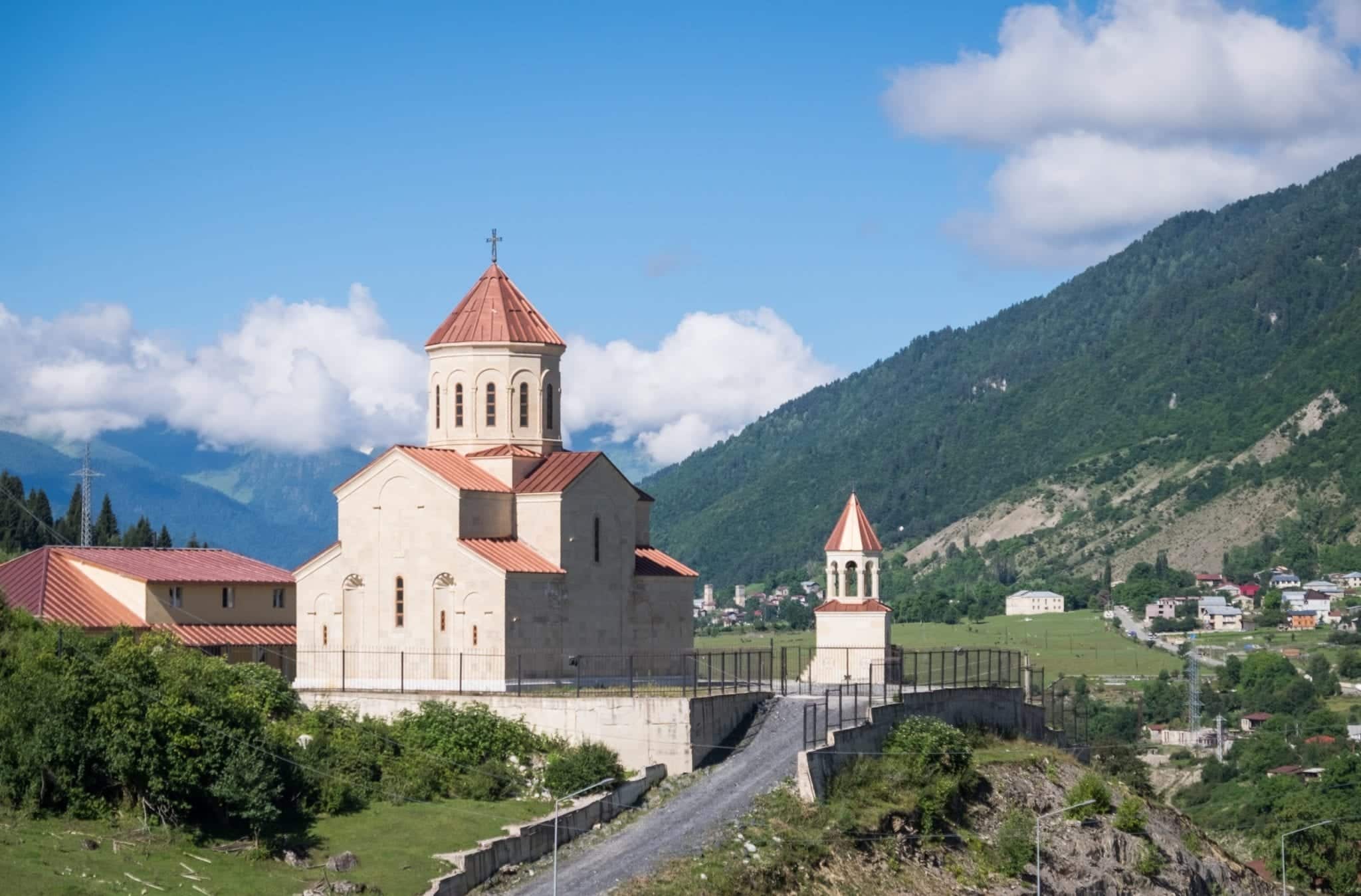 An orange-roofed church looking over the mountain landscape in Mestia, Svaneti.