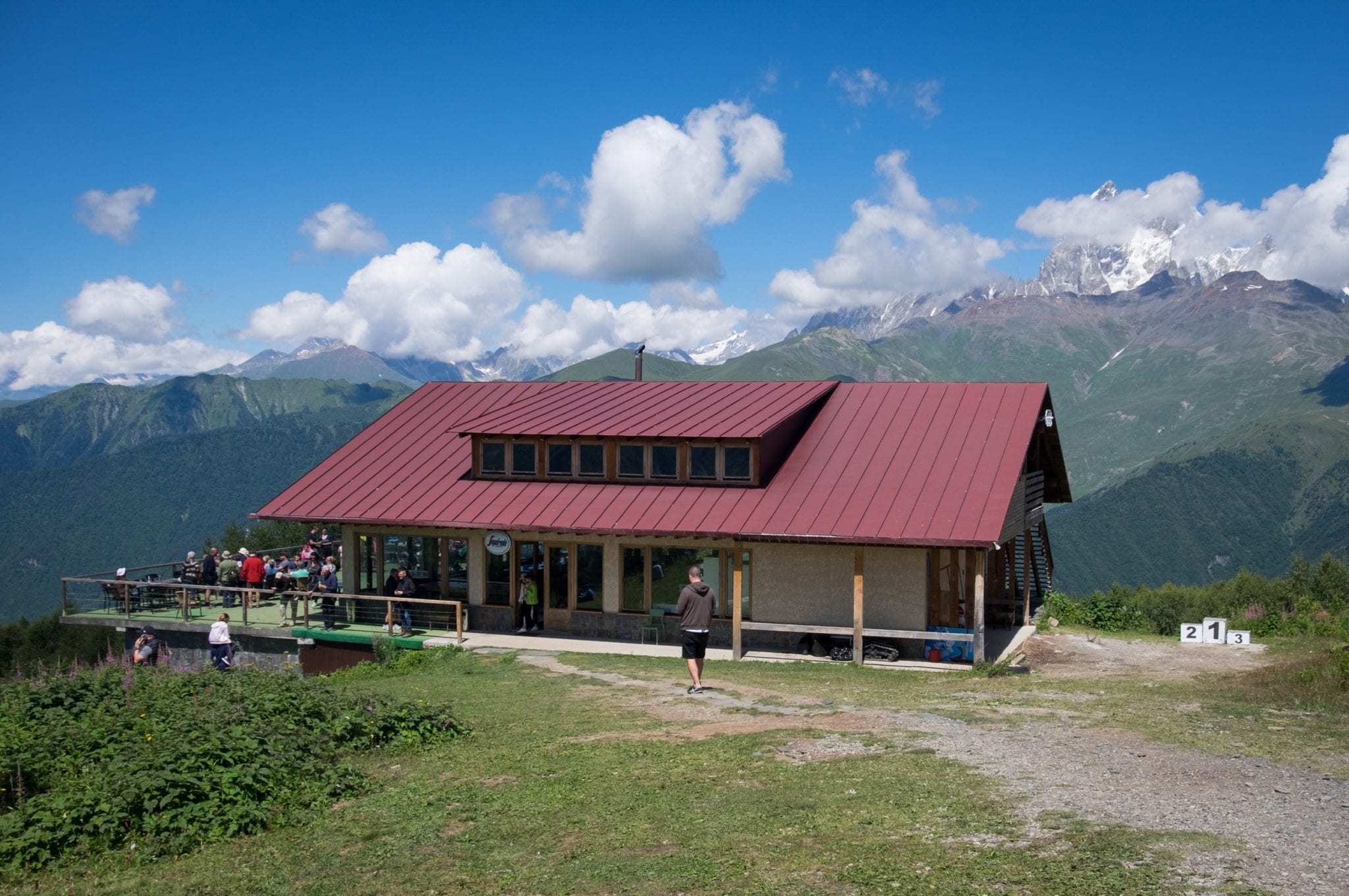 A restaurant with a maroon roof overlooks a Mountain View in Svaneti.