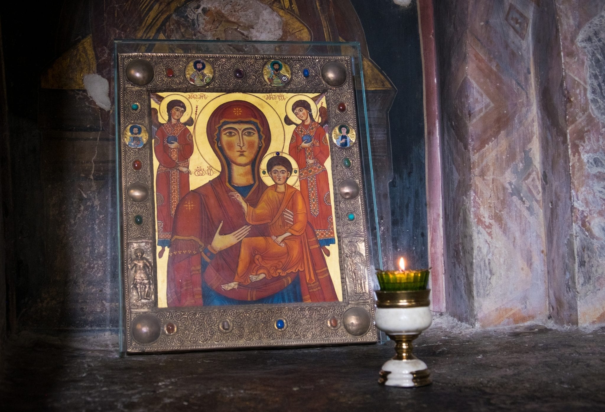A gold portrait of the Virgin Mary and Jesus leaning against a wall in a Georgian church, a chalice sitting in front.