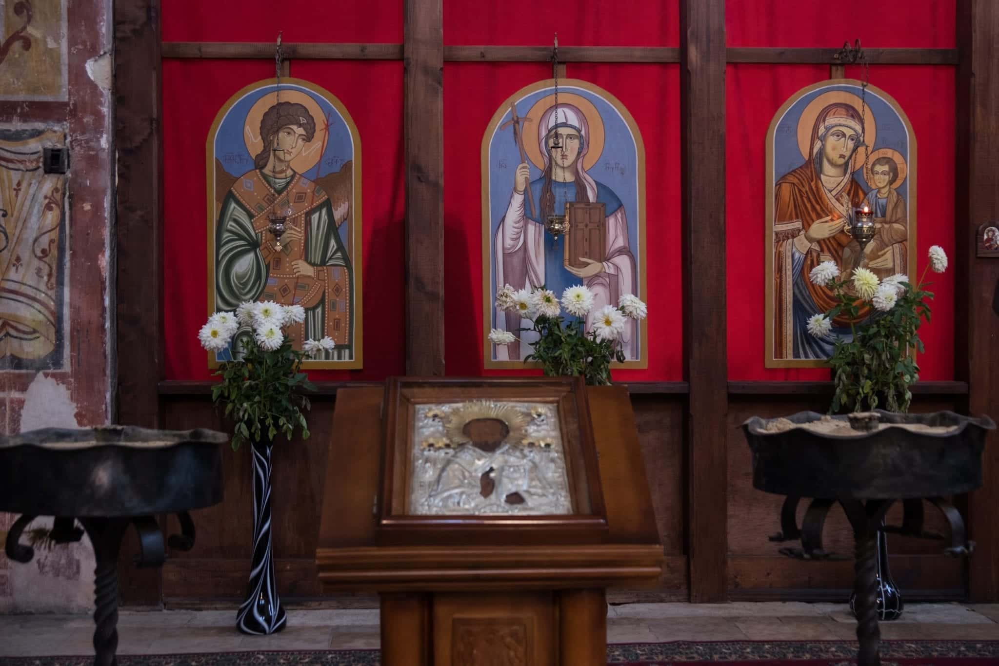 The altar at Gelati Monastery, with pictures of saints in front of blood-colored paneling.