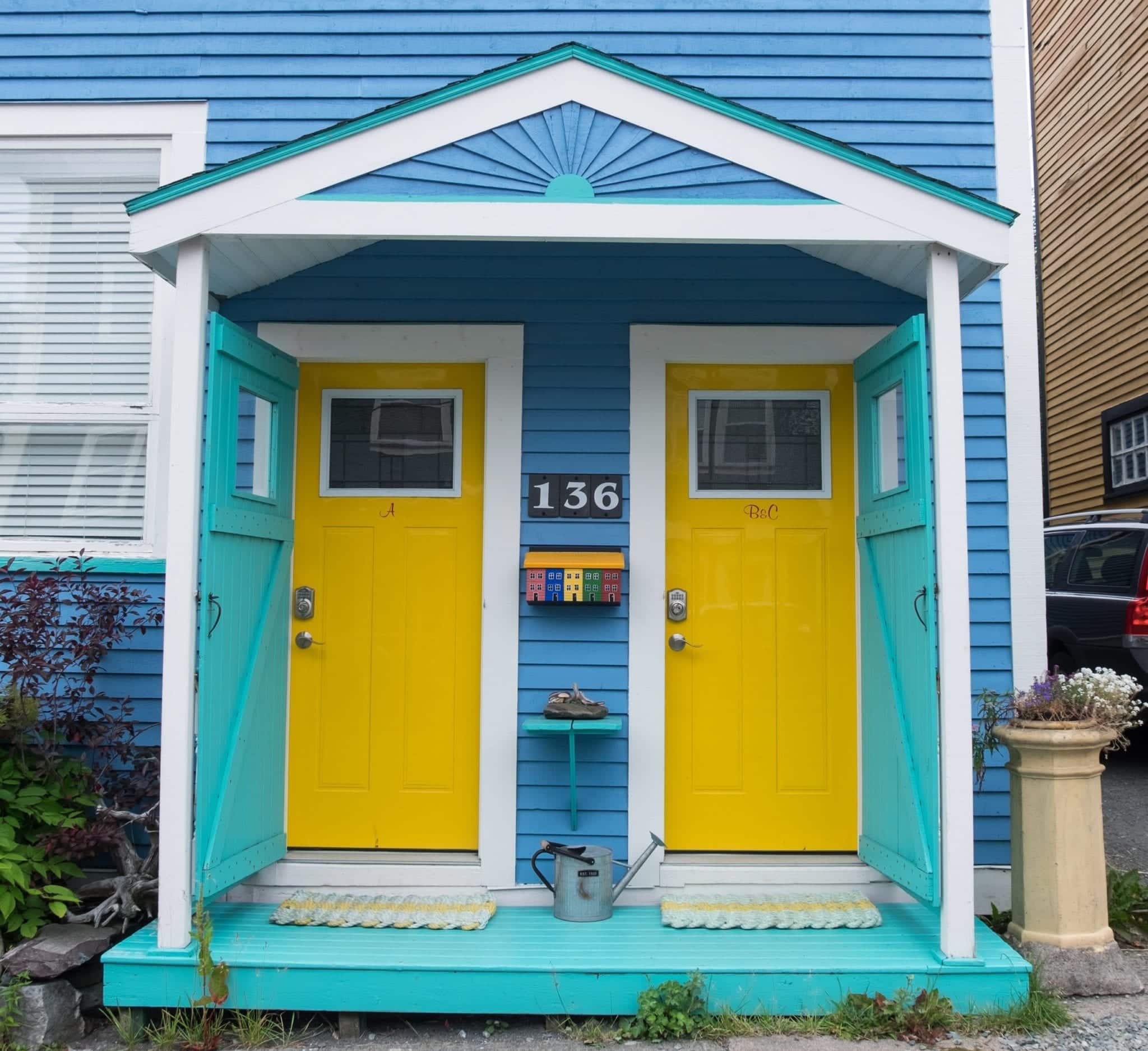 A blue house with two bright yellow doors side by side, surrounded by turquoise trim, in St. John's.