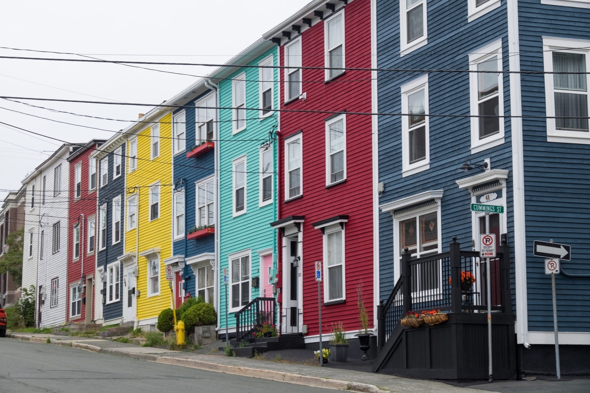 A row of brightly colored square houses in St. John's: yellowfins, blue, sea green, burgundy, and navy.