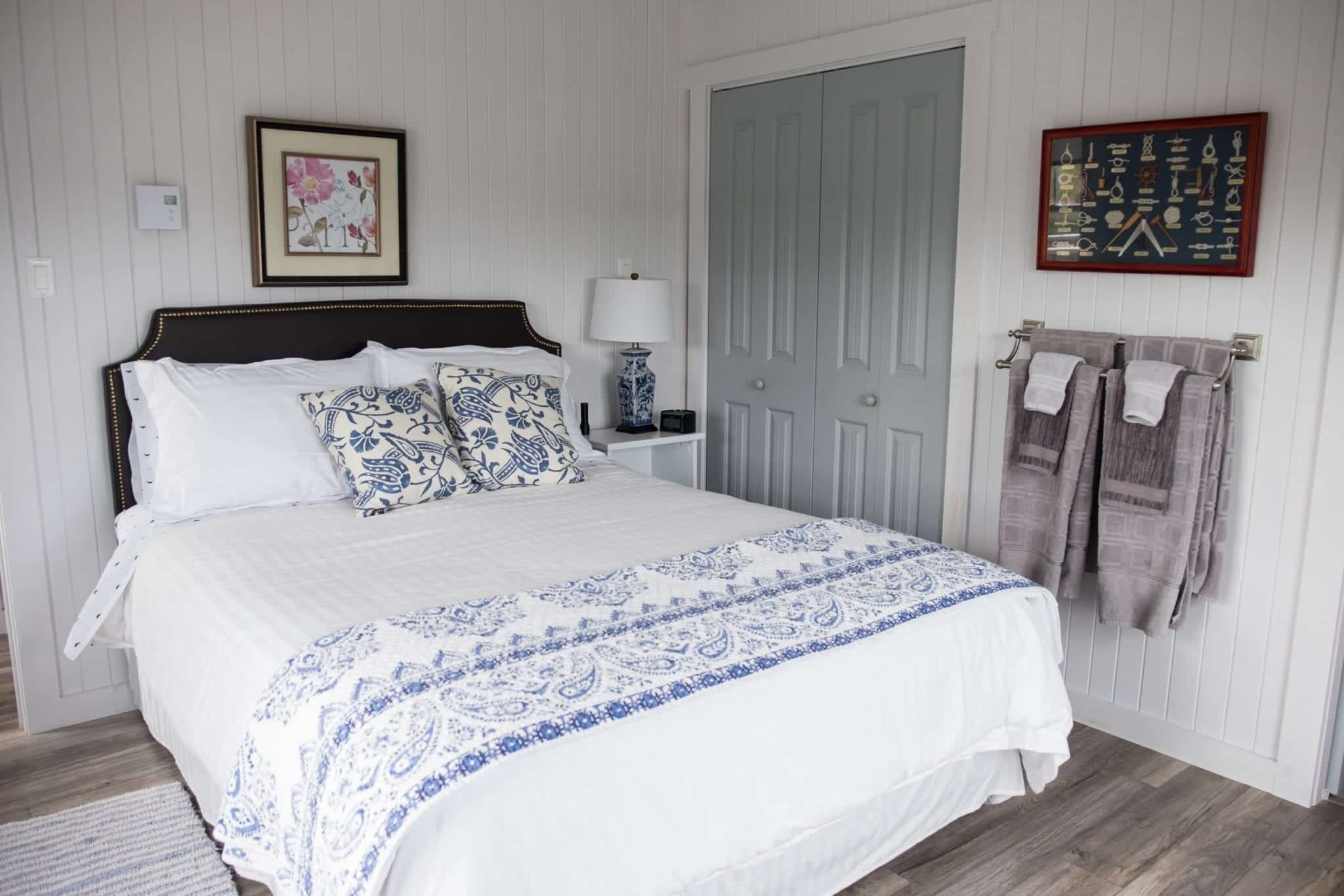 A white queen bed in a white and blue-decorated bedroom at the Artisan Inn.