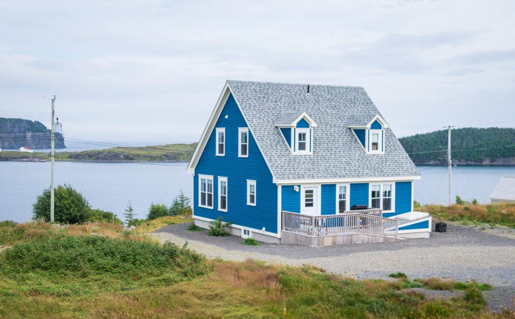 A deep blue cottage perched on the edge of the bay in Trinity, Newfoundland