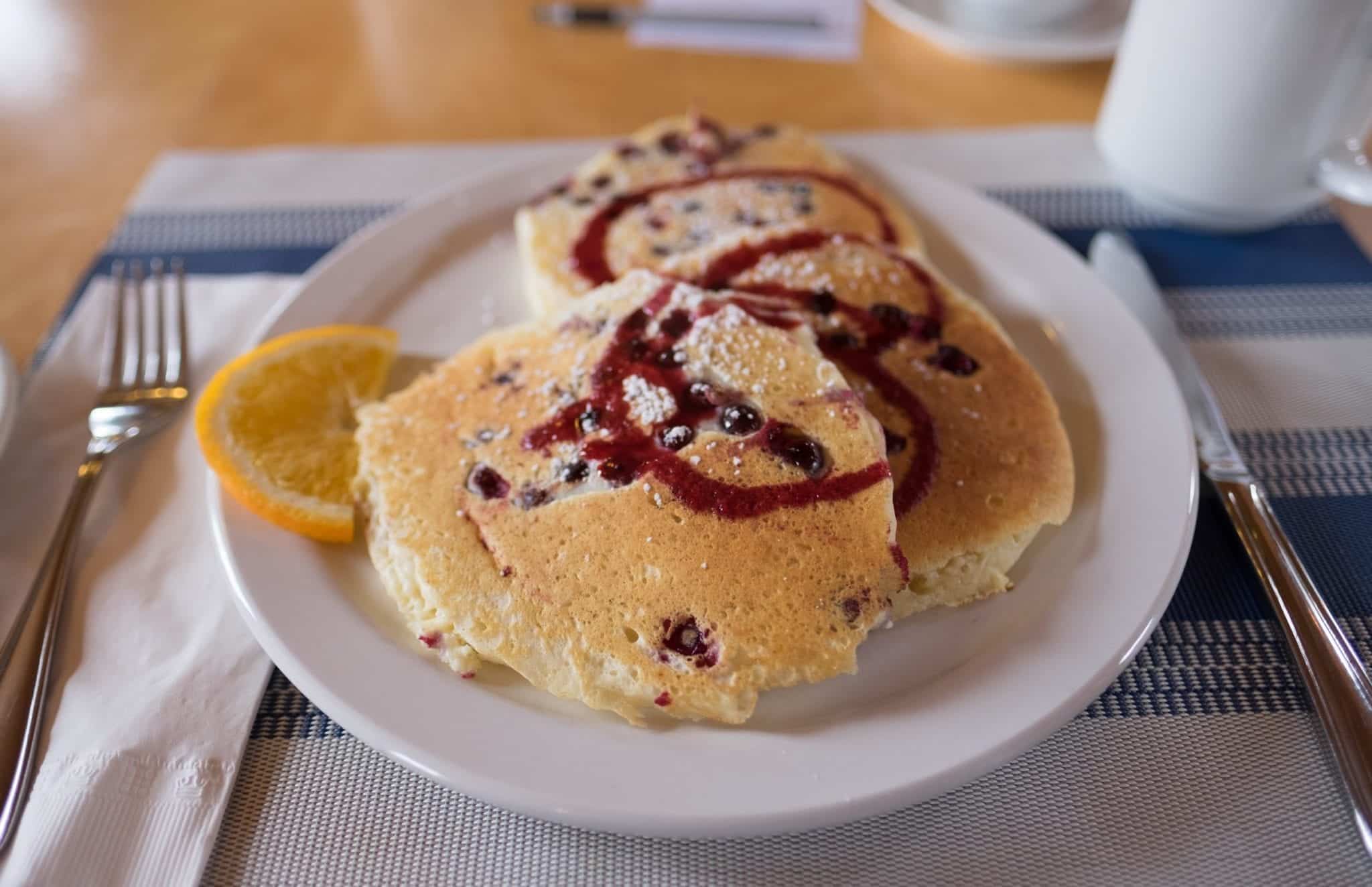 Pancakes studded with partridgeberries and a swirl of syrup on top.