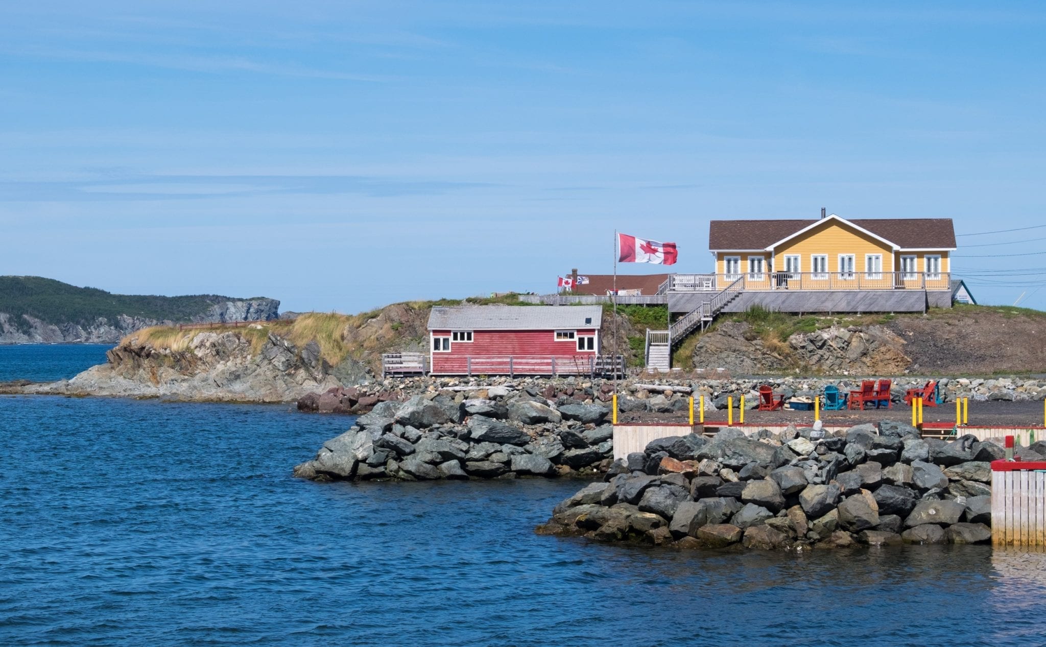 Red and yellow cottages on the water's edge, a Canadian flag flying.