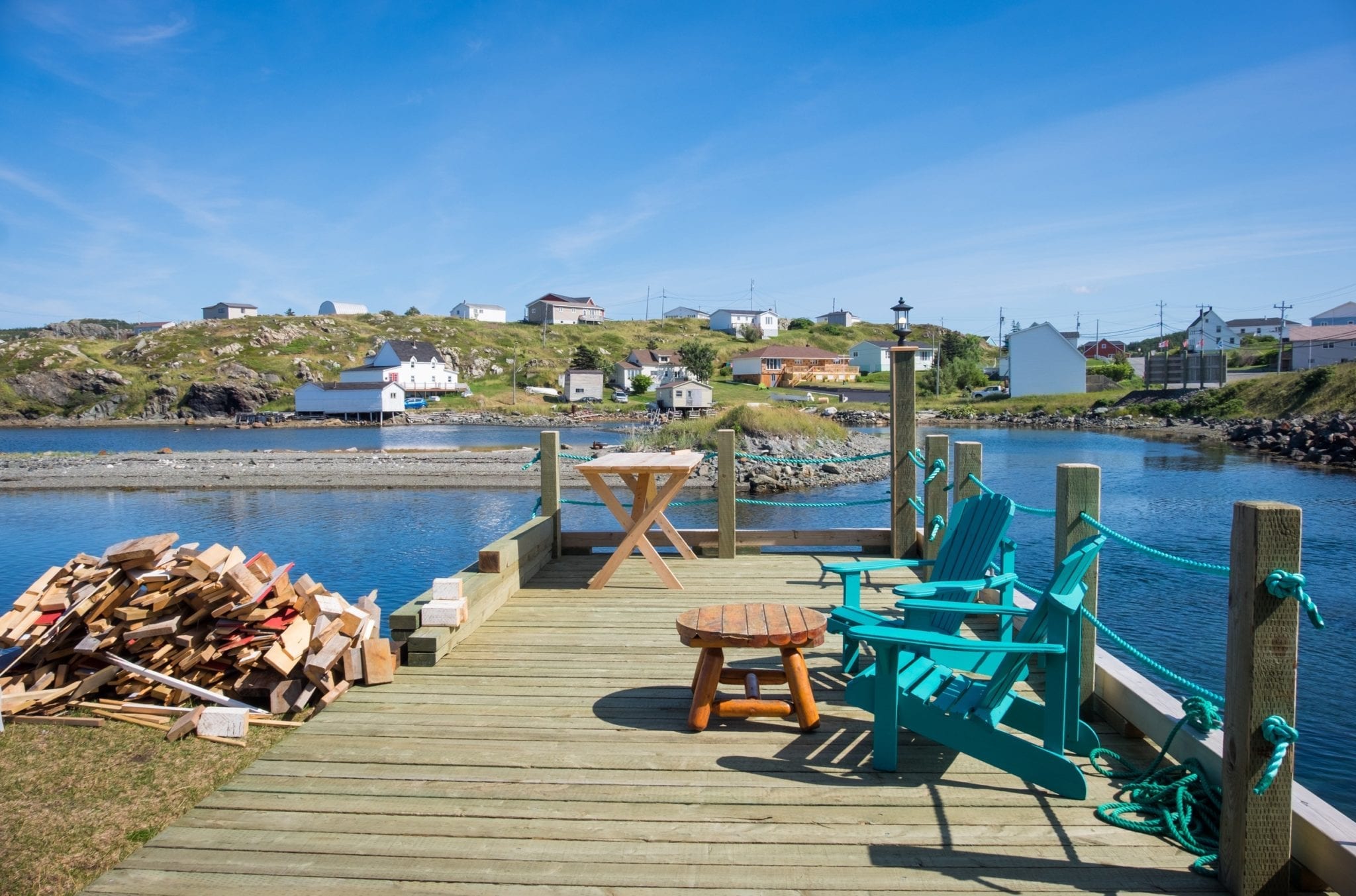 A patio in front of the pay with turquoise chairs and a wooden table.