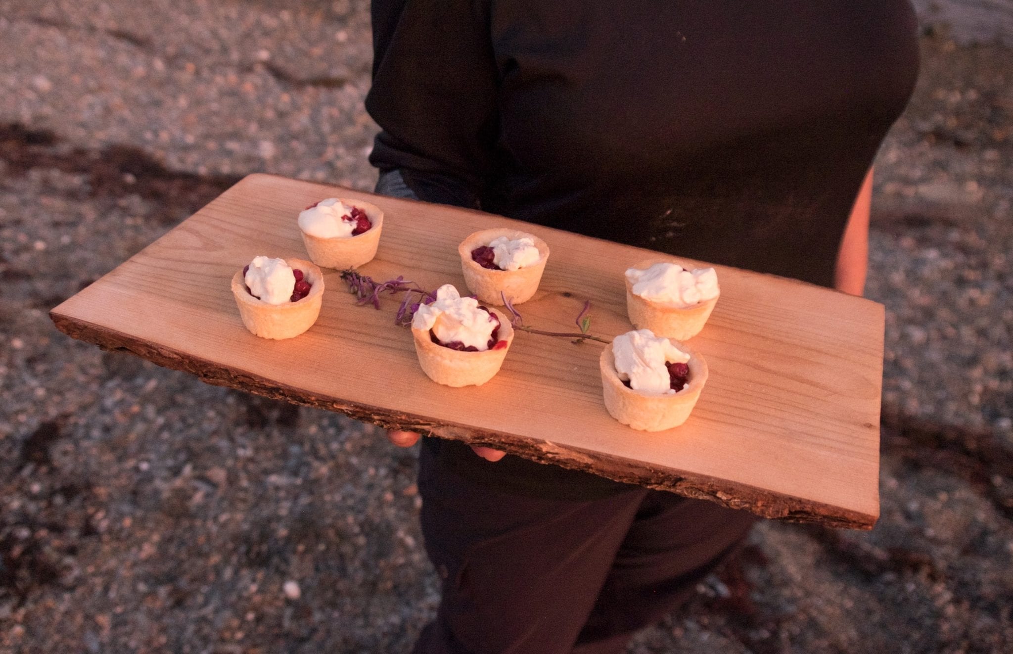 Crystal holds a wooden slab topped with six tiny tartlets filled with partridgeberries and topped with cream.