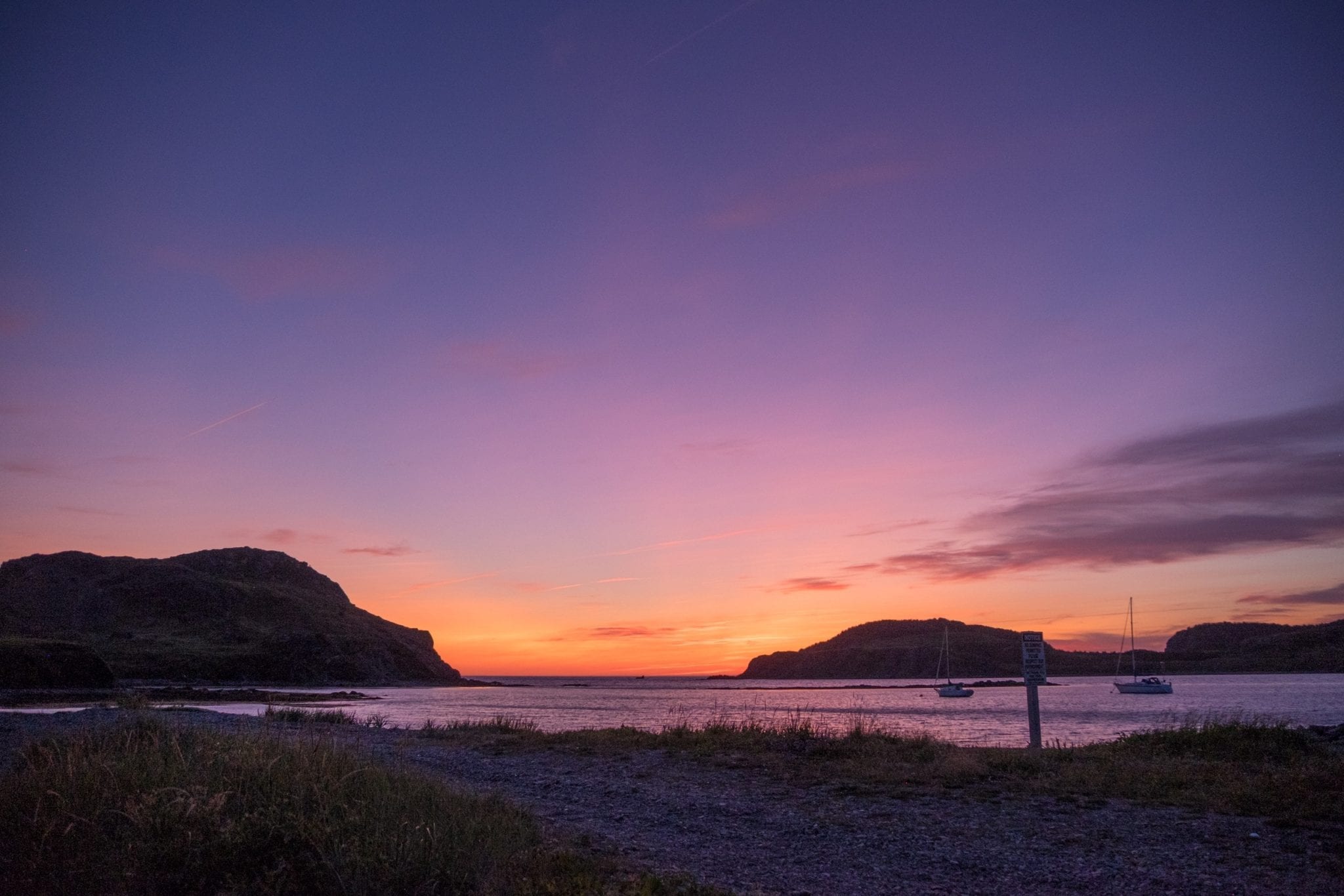 Sunset on the beach, most of the sky purple, a bit of orange and yellow at the water's edge.