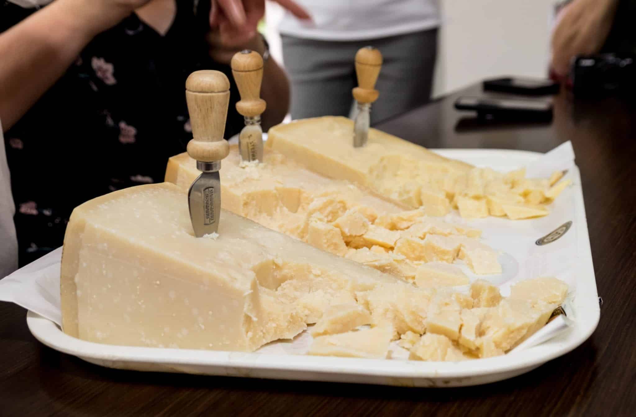 Three wedges of cheese in a row, each broken up into bite-size pieces.