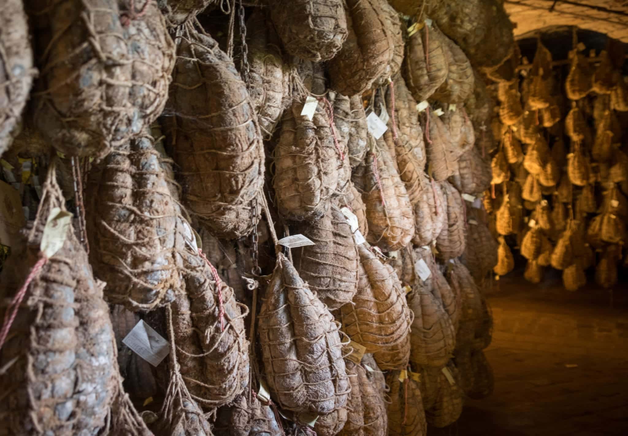 Racks of Culatello hams hanging in a cellar.