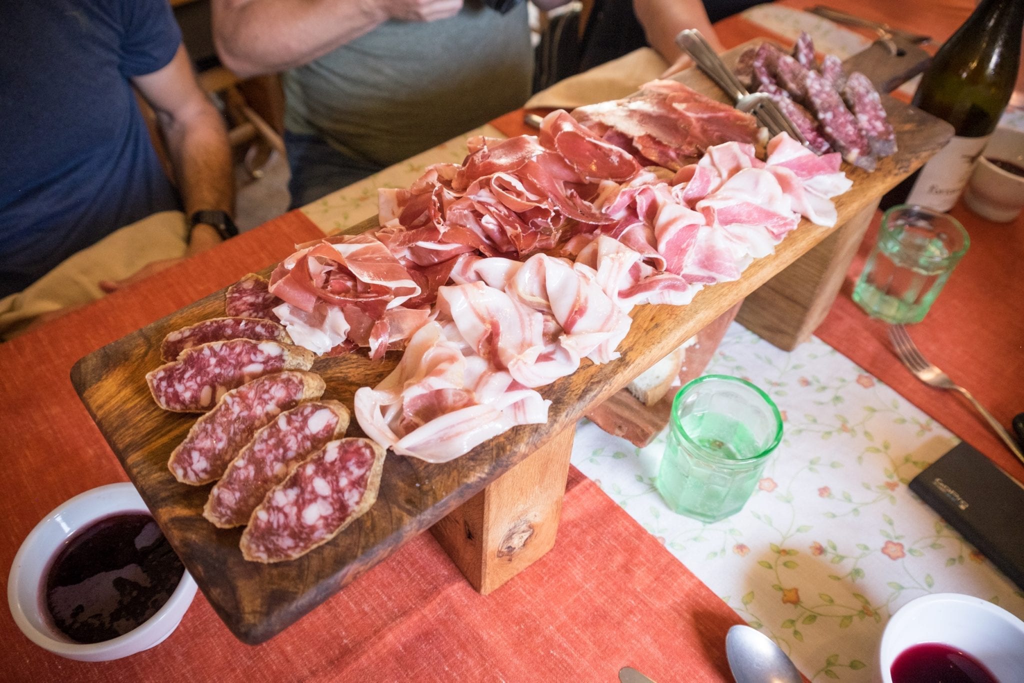 A large wooden platter covered with several cured meats, including culatello, salami, and raw pancetta (white and slithery and gross, but hey, some people are into that).