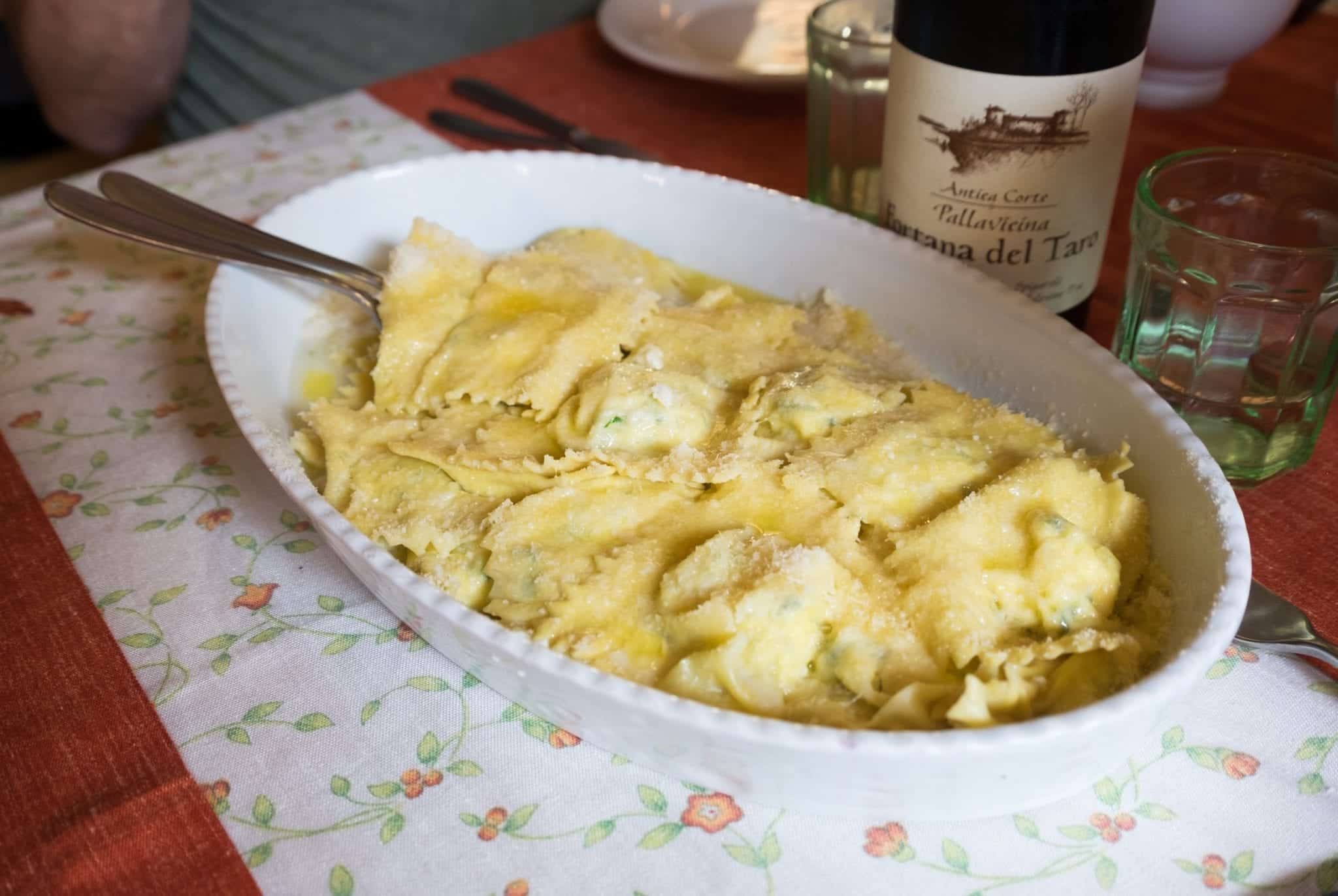 An oval bowl filled with tortilli pasta, topped with lots of parmigiano cheese.