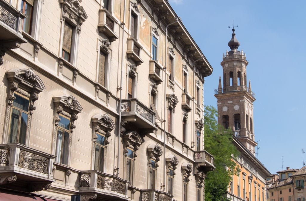 A view of Parma's crenellating side buildings with a steeple in the distance.